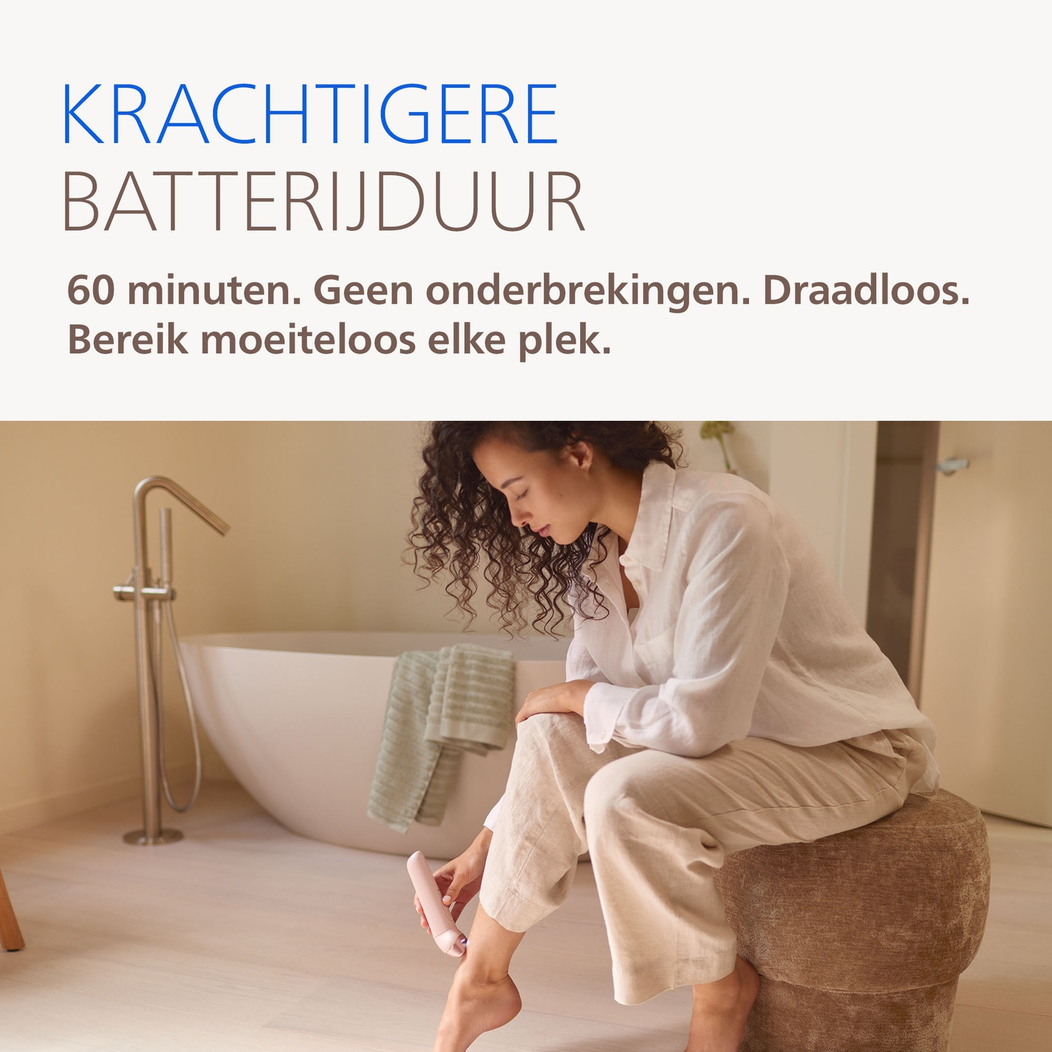 A woman sits on a stool using a pink epilator on her leg. A bathtub is in the background.