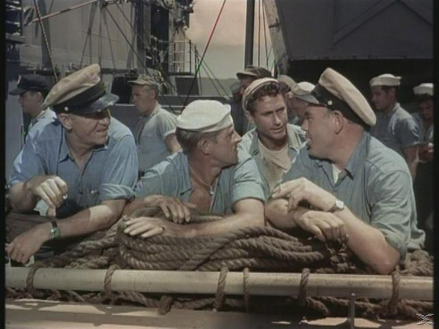 Männer in Uniformen sprechen an Deck eines Schiffes, umgeben von Seilen.