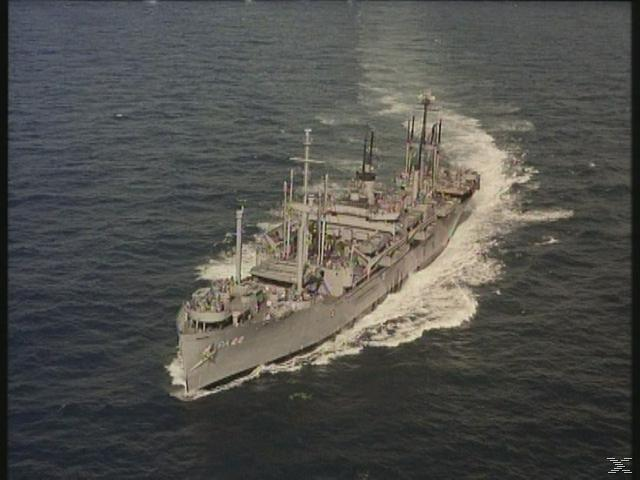 Ein großes graues Marineschiff fährt durch das Meer und hinterlässt eine weiße Spur.