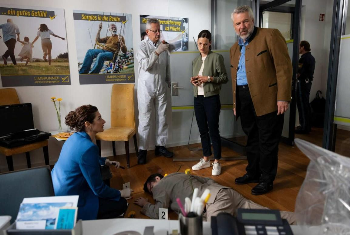Polizei untersucht Tatort: Mann liegt am Boden, Ermittler und Zeugen im Raum.
