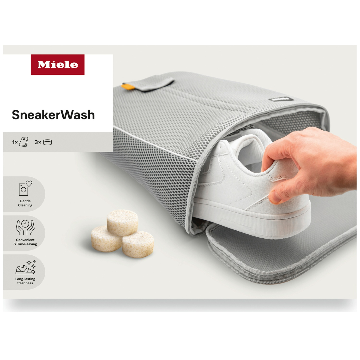 Une main place une basket blanche dans un sac Miele SneakerWash gris.