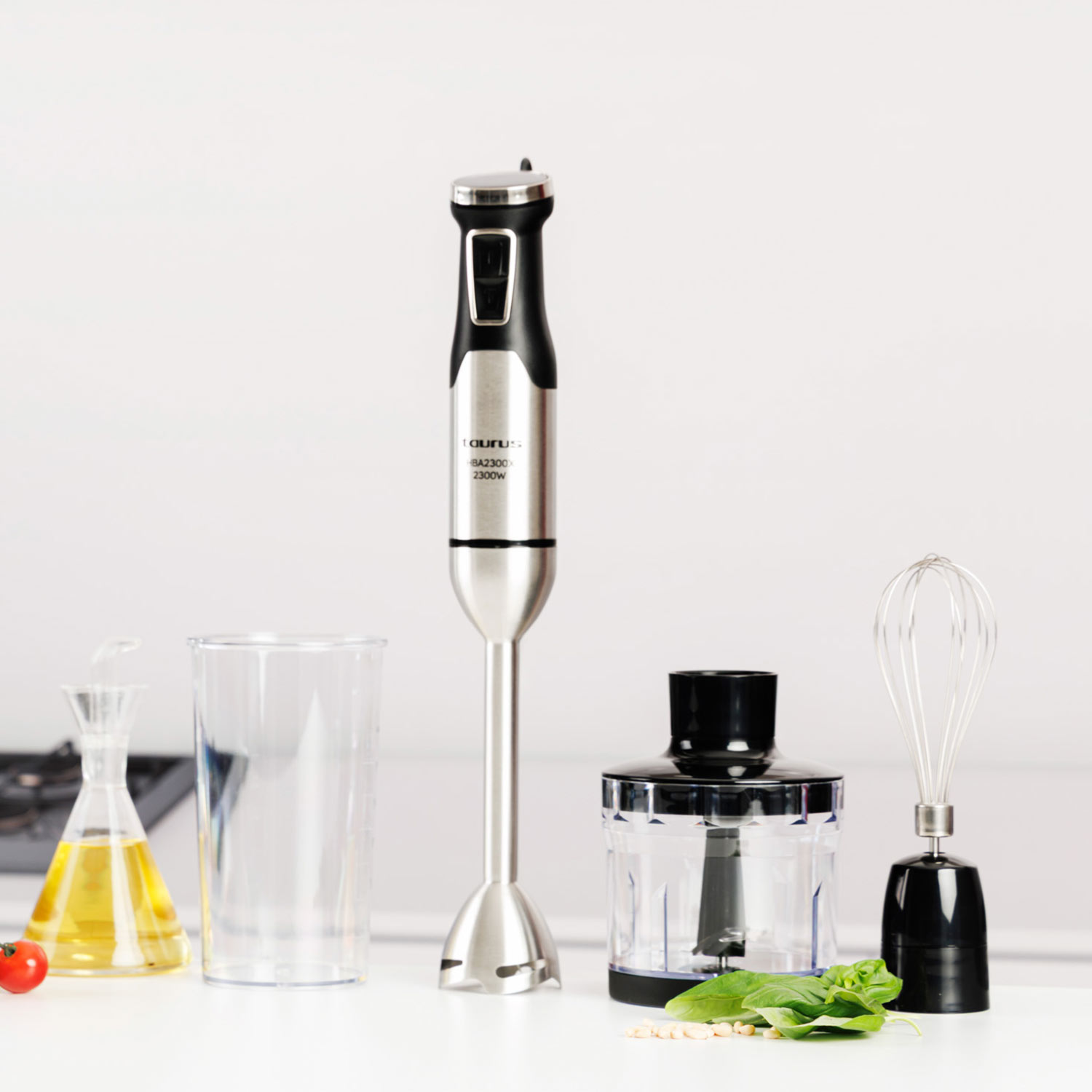 Un set de batidora de inmersión con accesorios, incluyendo vaso, botella de aceite y tomate.