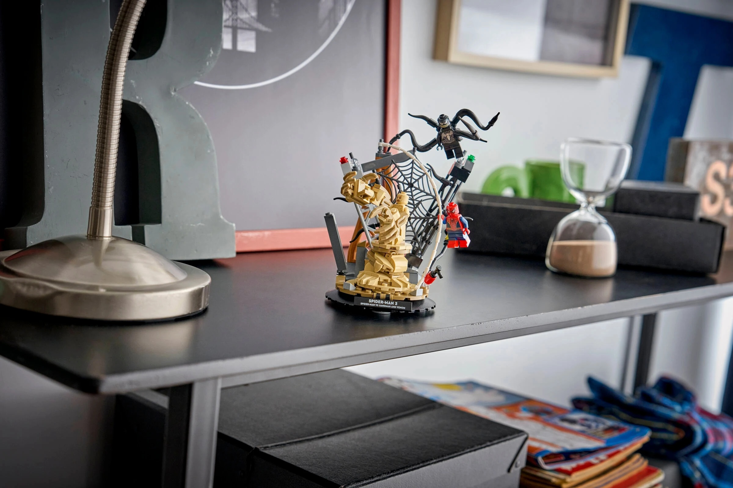 Zestaw Lego ze Spider-Manem, Sandmanem i Venomem na półce z dekoracjami.