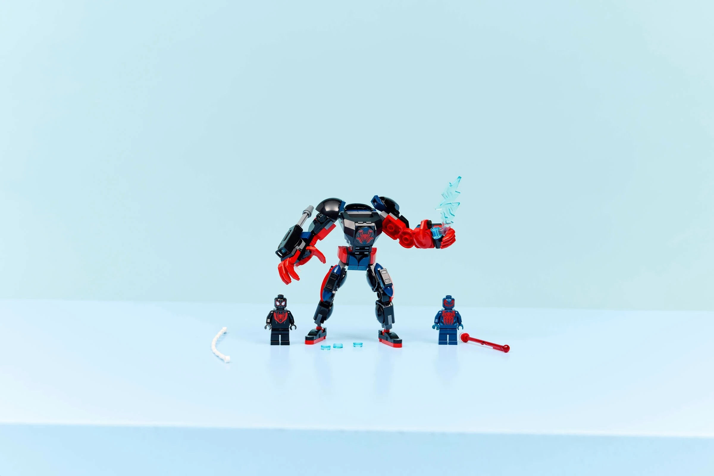 Mech Lego z figurkami Spidermana i akcesoriami na jasnoniebieskim tle.