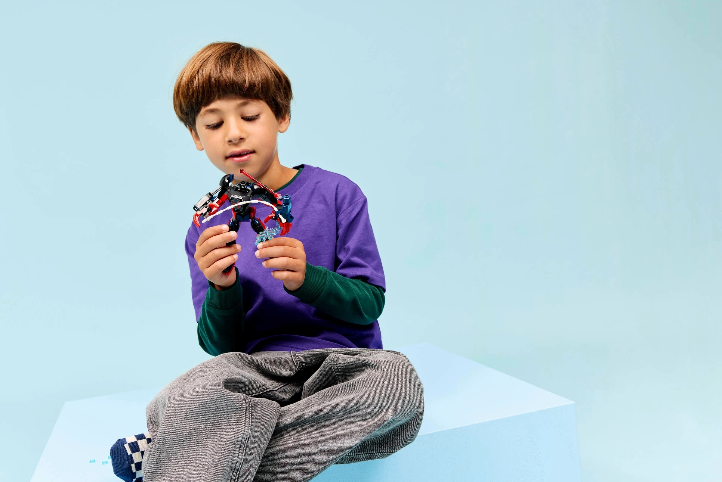 Chłopiec siedzi, trzymając kolorowy model robota-zabawki.