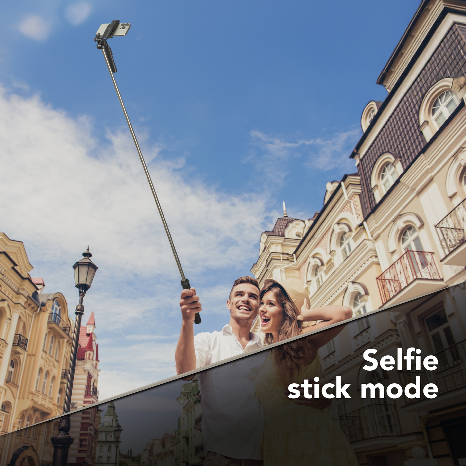 Una coppia scatta un selfie con un selfie stick davanti agli edifici.