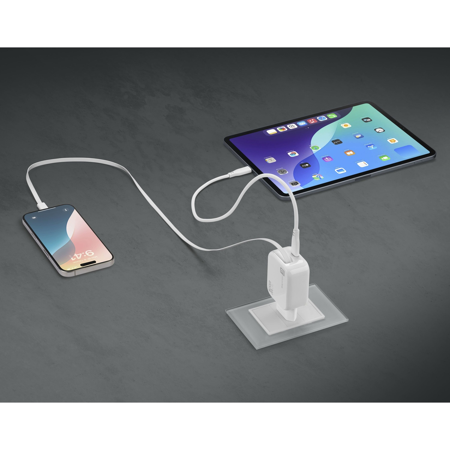 Un adattatore di ricarica bianco collega un iPhone e un iPad tramite cavi bianchi.