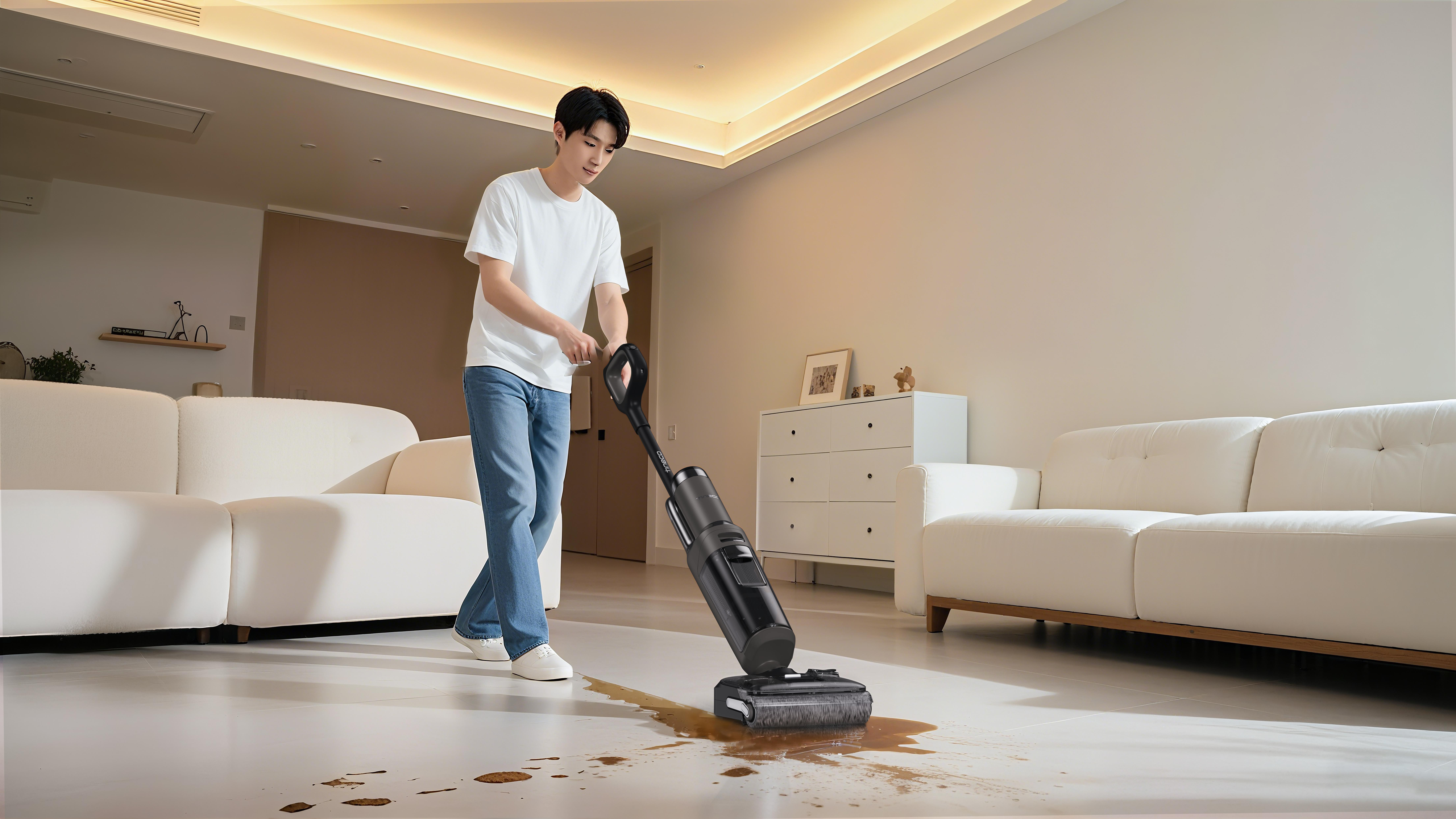 Mann reinigt verschüttete Flüssigkeit mit einem Nasssauger in einem modernen Wohnzimmer.