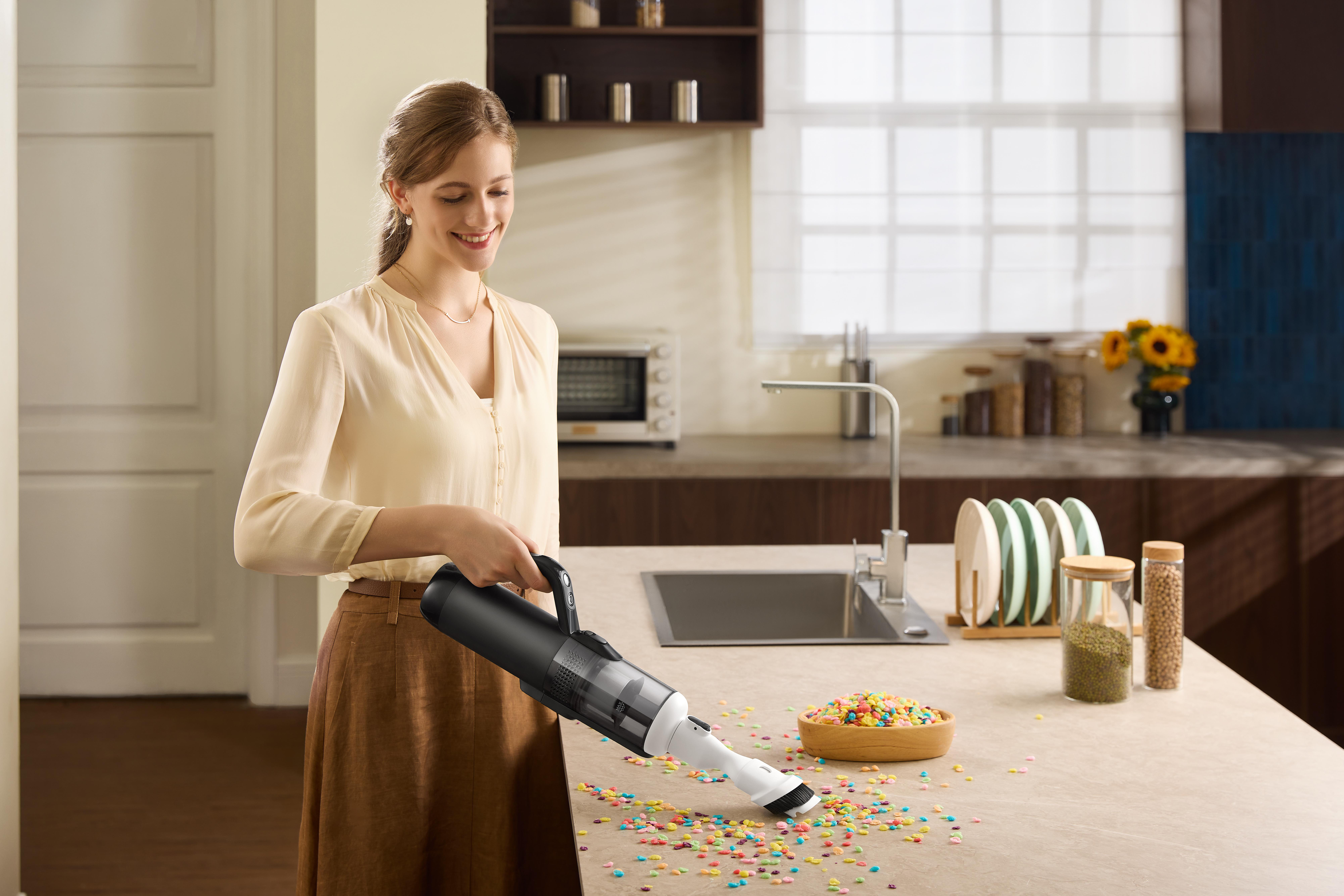 Eine Frau saugt bunte Streusel mit einem Handstaubsauger auf.