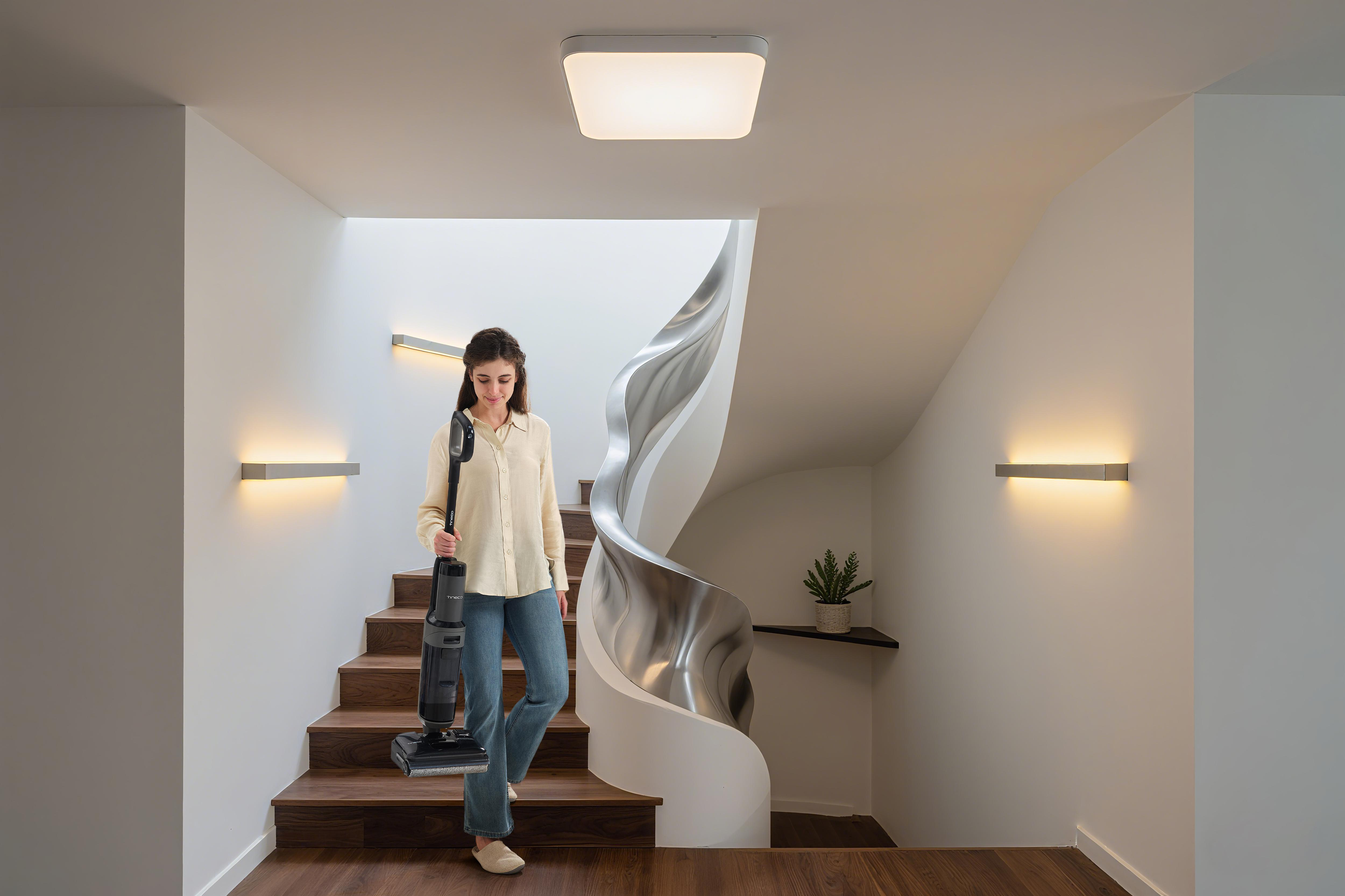 Frau mit Staubsauger auf einer Holztreppe mit geschwungener Metallwand.