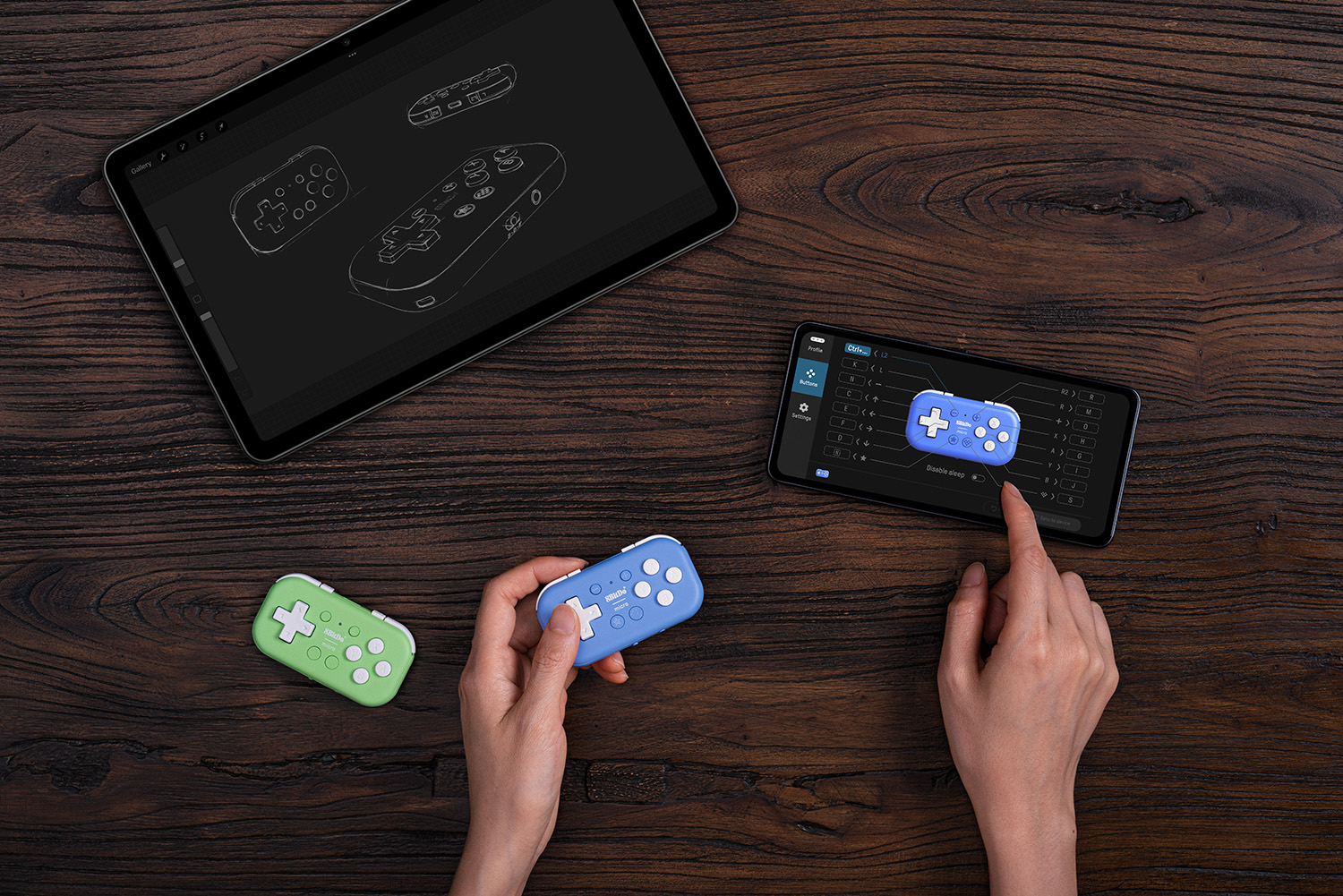 Zwei kleine Gamecontroller, einer blau, einer grün, liegen auf einem Holztisch.