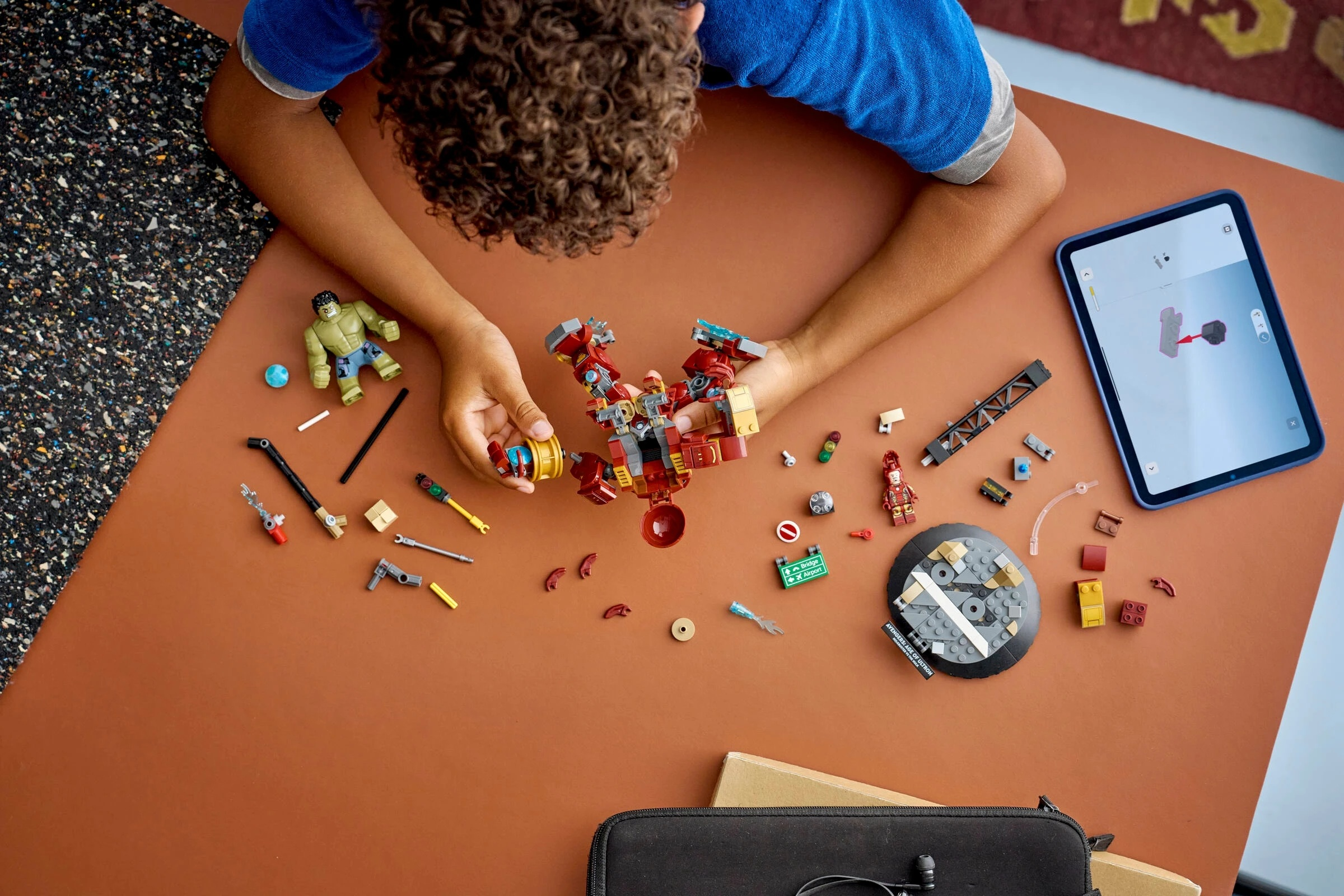 Dziecko buduje z kolorowych klocków Lego. Tablet wyświetla instrukcje.