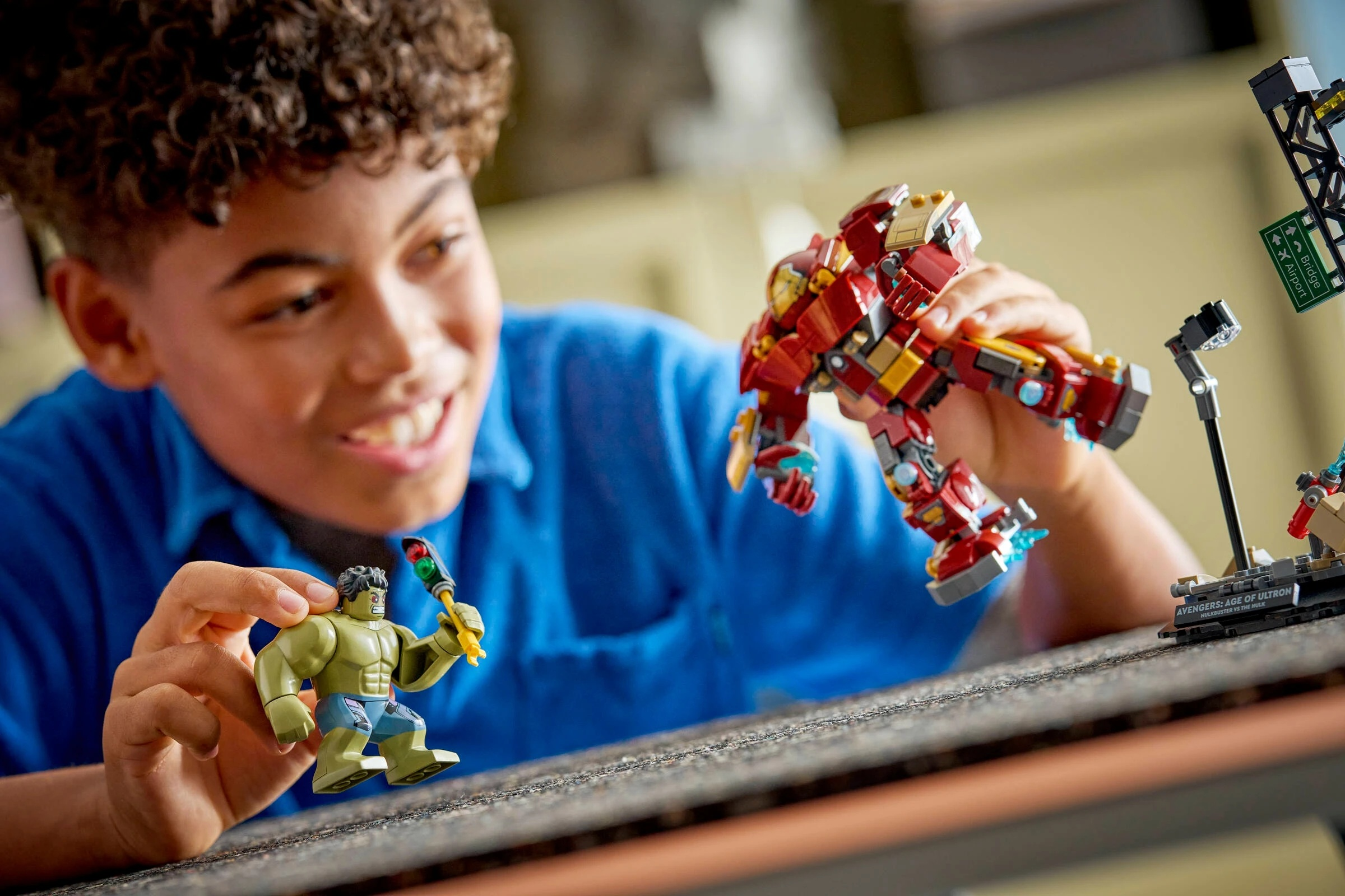 Chłopiec bawi się figurkami Lego: Hulk i Hulkbuster.