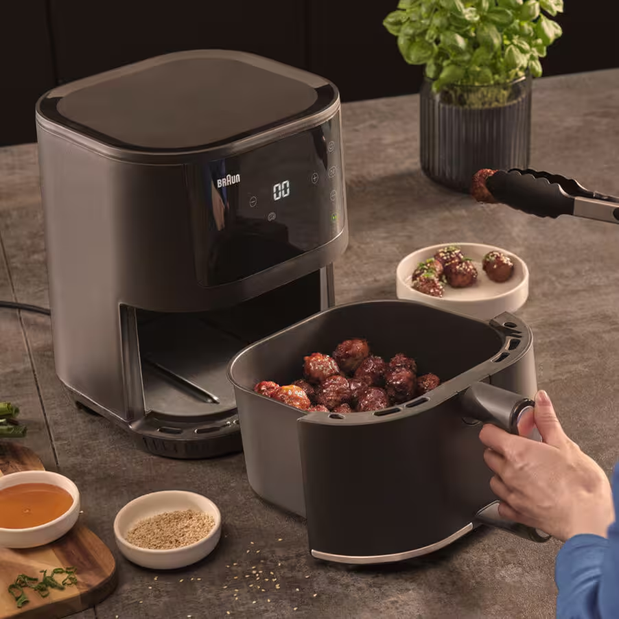 Une friteuse à air foncée avec des boulettes de viande retirées.