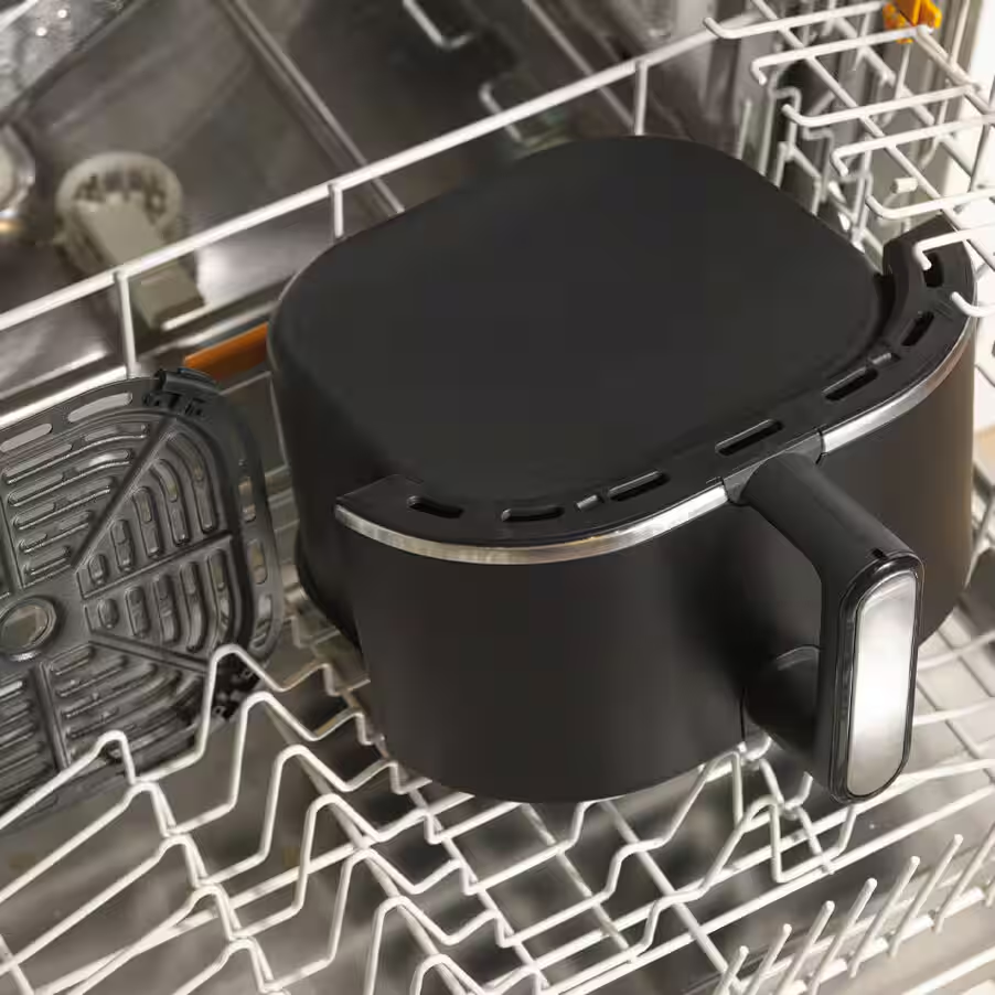 Une friteuse à air noire et sa grille sont dans un lave-vaisselle.