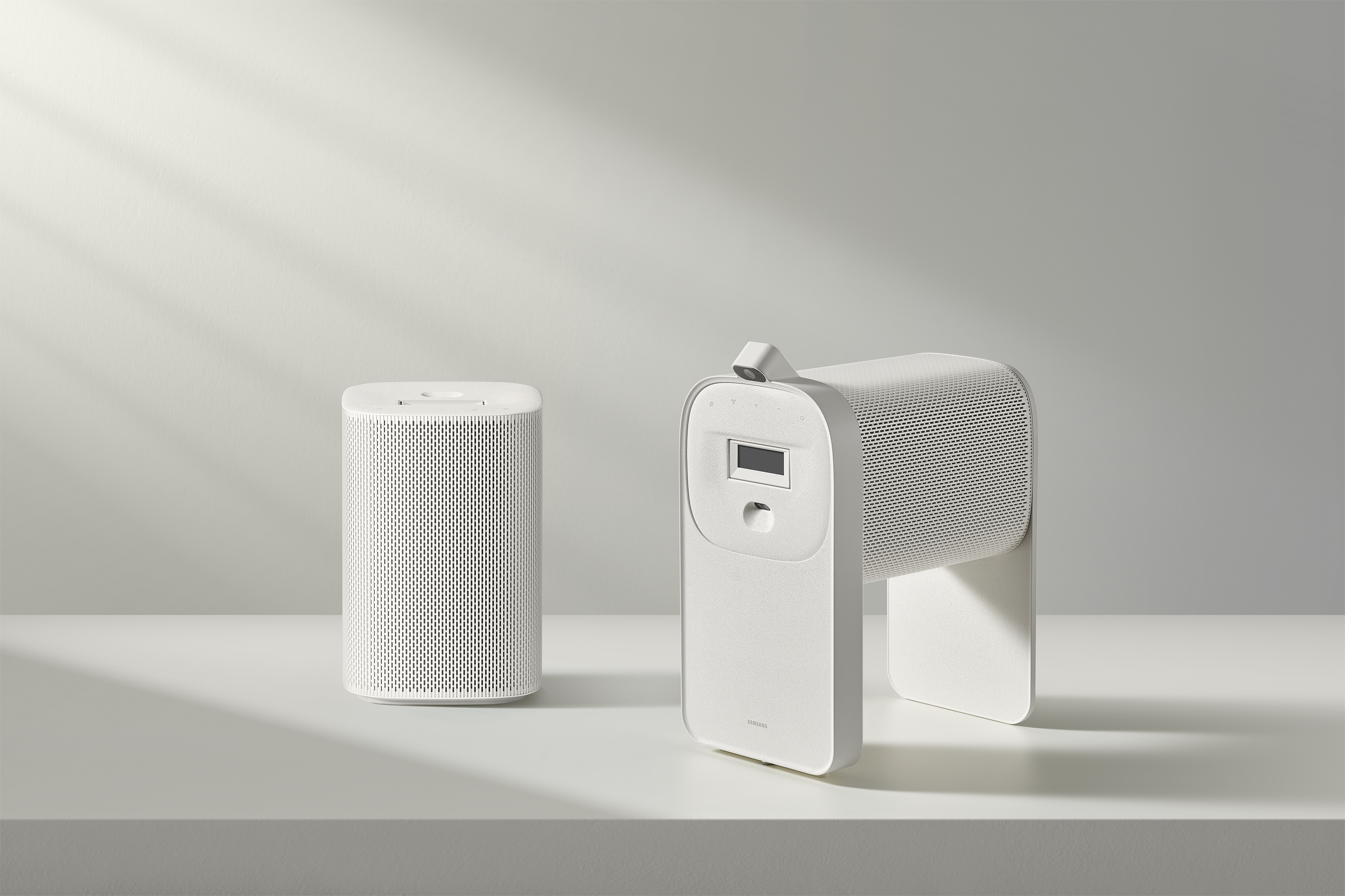 Dwa białe głośniki na półce; jeden cylindryczny, drugi z ekranem.