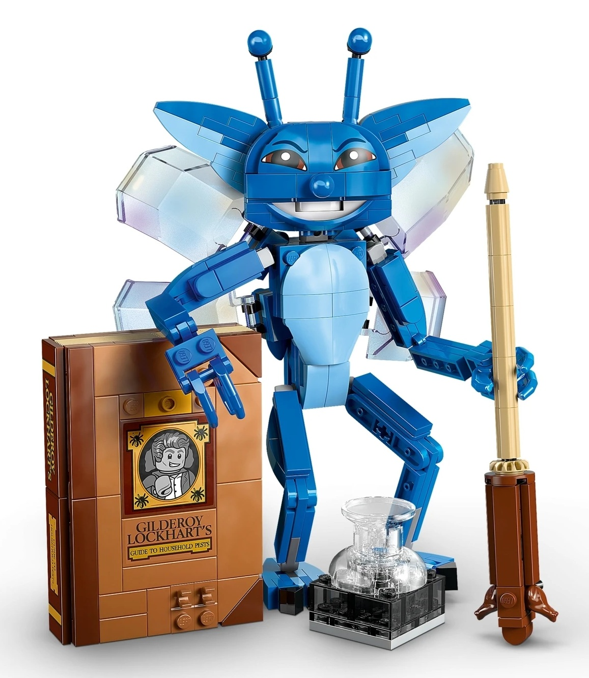 Niebieska stwora Lego ze skrzydłami stoi obok brązowej księgi i różdżki.