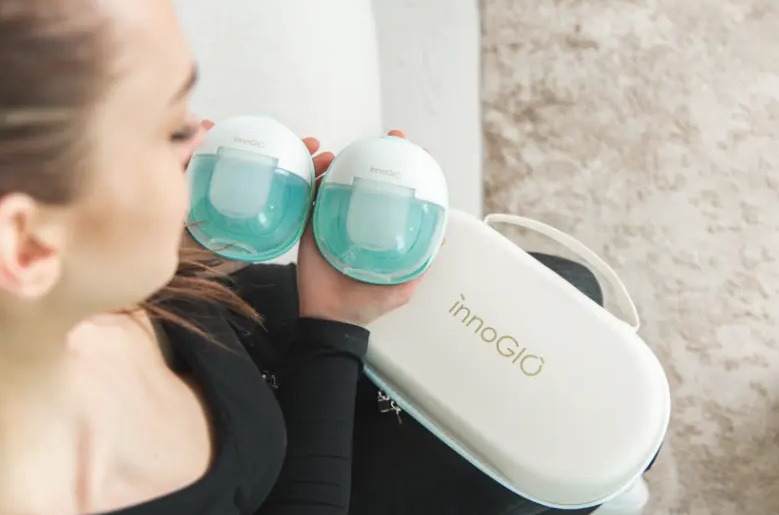 Kobieta trzyma dwie białe i turkusowe laktatory oraz białą torbę.