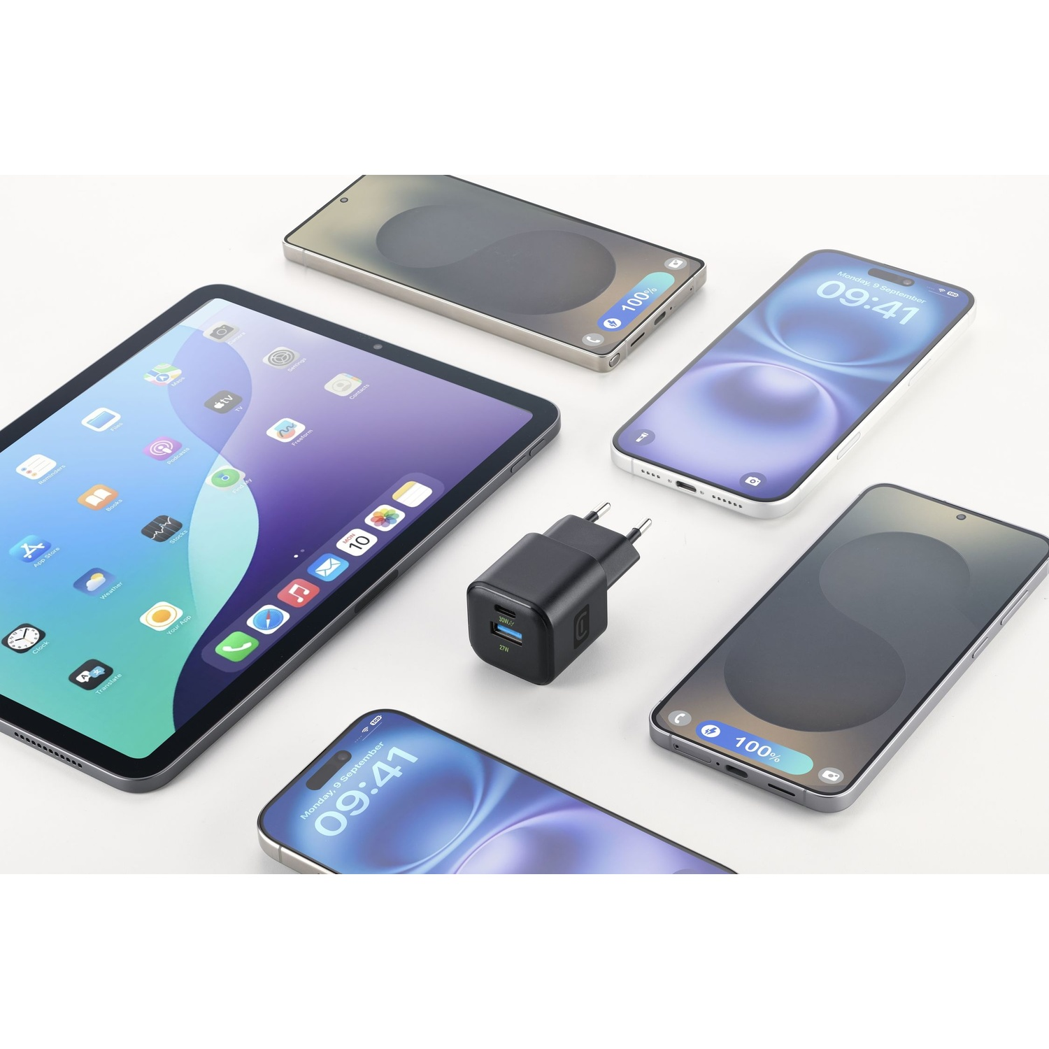 Un tablet, un caricabatterie e tre smartphone sono disposti su una superficie bianca.