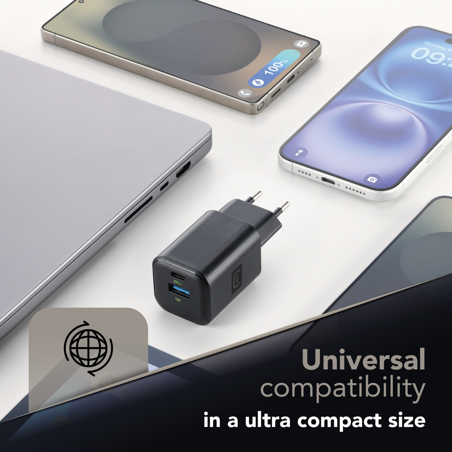 Un caricabatterie nero con due porte USB accanto a due smartphone e un laptop.