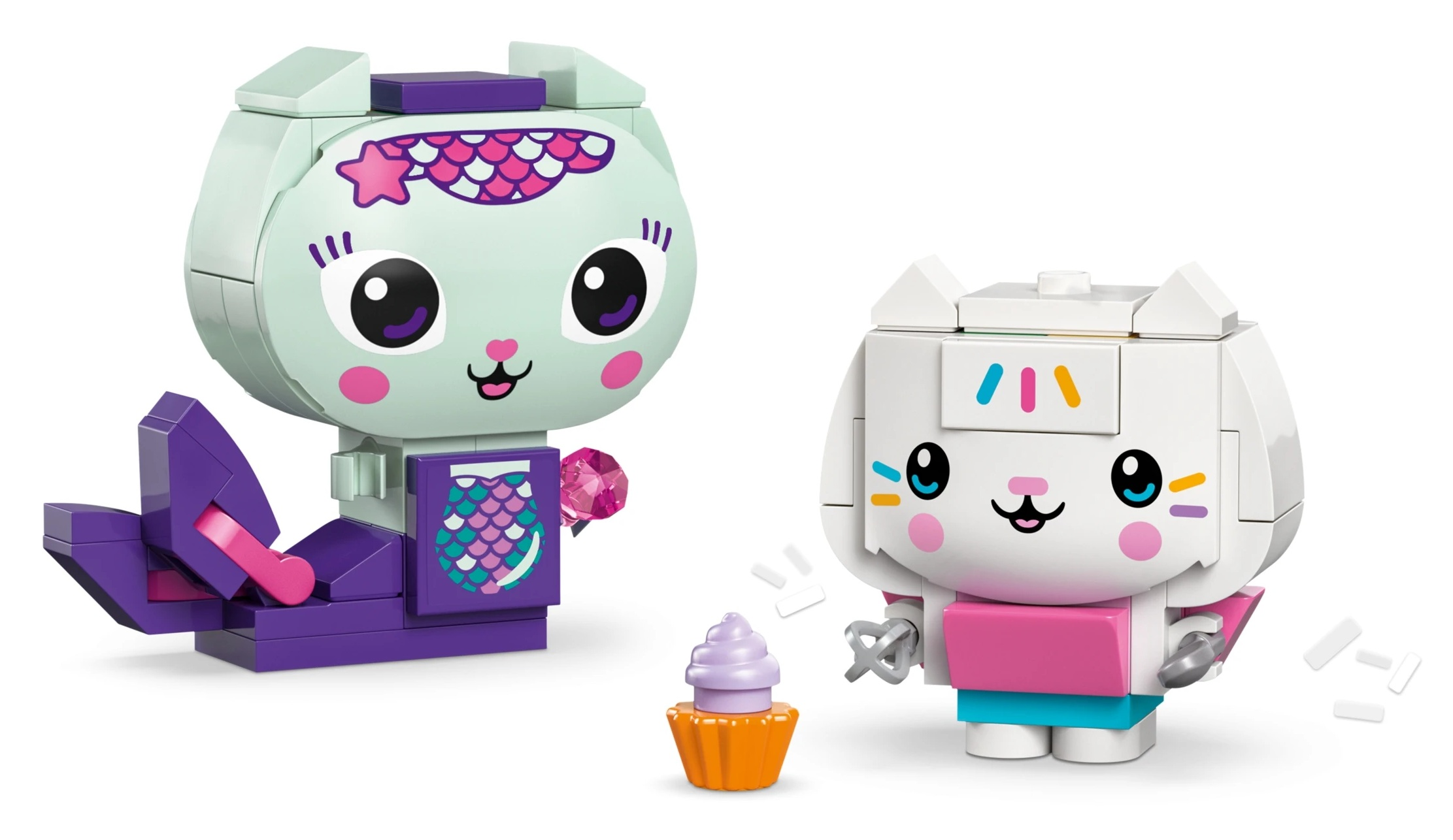 Dwie kolorowe figurki kotów Lego, jedna syrenka z babeczka, druga z posypka.