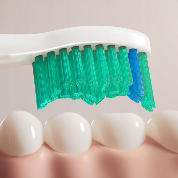 Biała szczoteczka do zębów z zielonymi i niebieskimi włoskami czyści białe zęby.