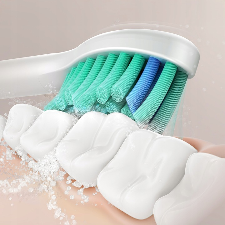 Białe zęby są czyszczone przez szczoteczkę elektryczną z zielonymi i niebieskimi włoskami.