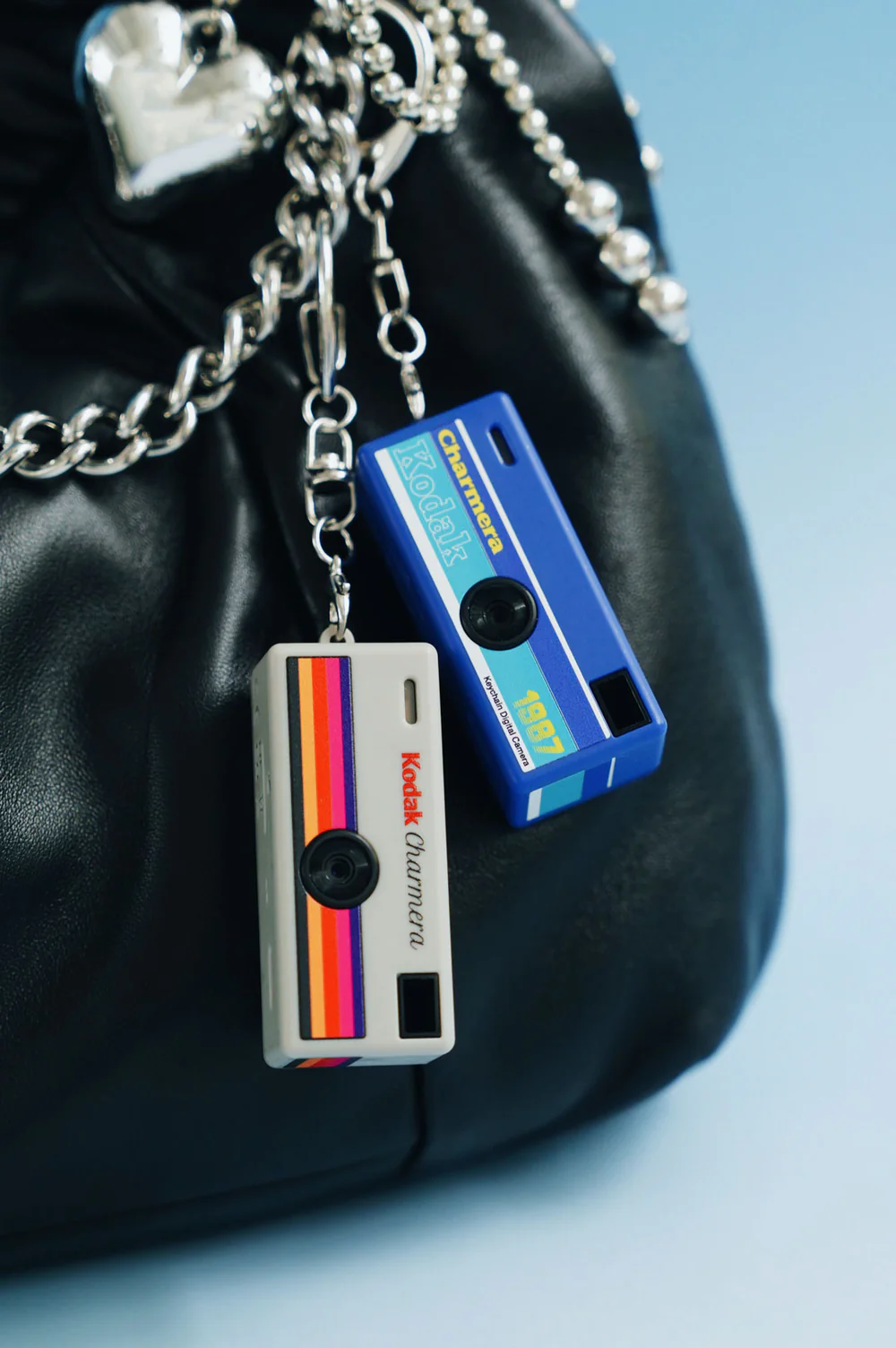 İki Kodak Charmer mini kamera, siyah bir çantadan sarkıyor.