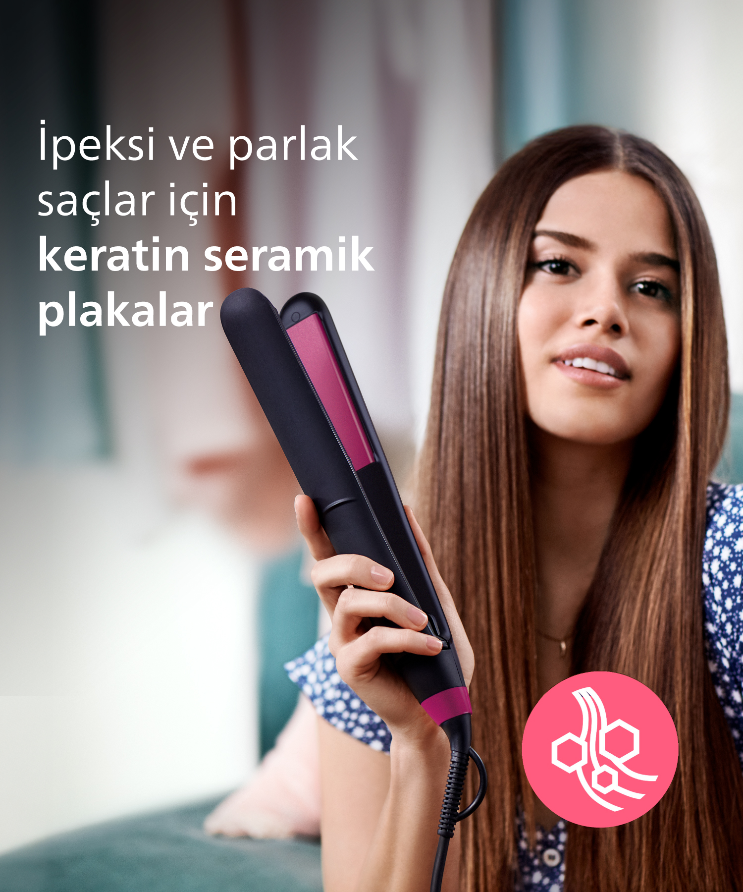 Kadın, pürüzsüz saçlar için pembe ve siyah plakalı saç düzleştirici tutuyor.