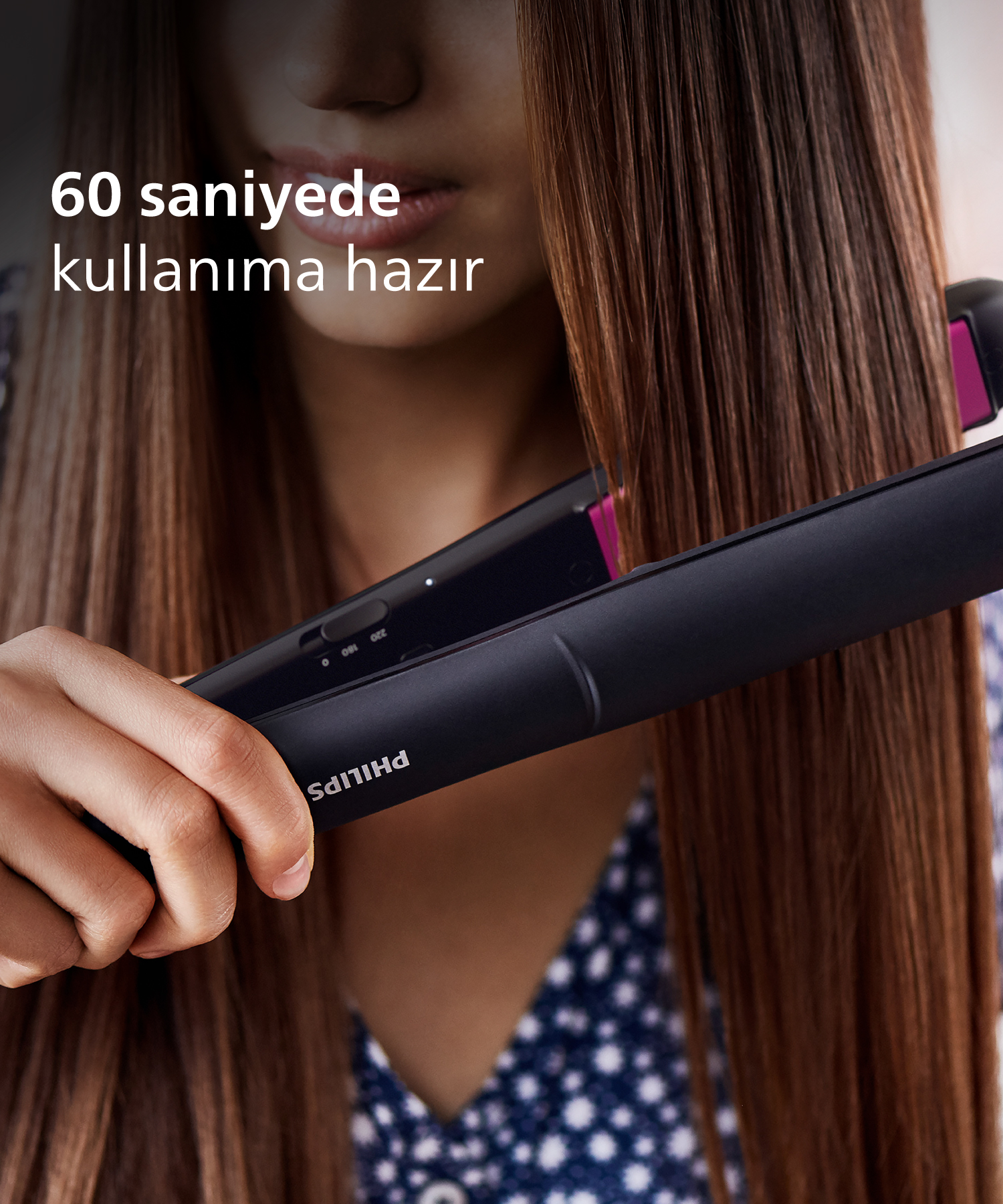 Kadın, siyah Philips düzleştiriciyle kahverengi saçlarını düzleştiriyor.