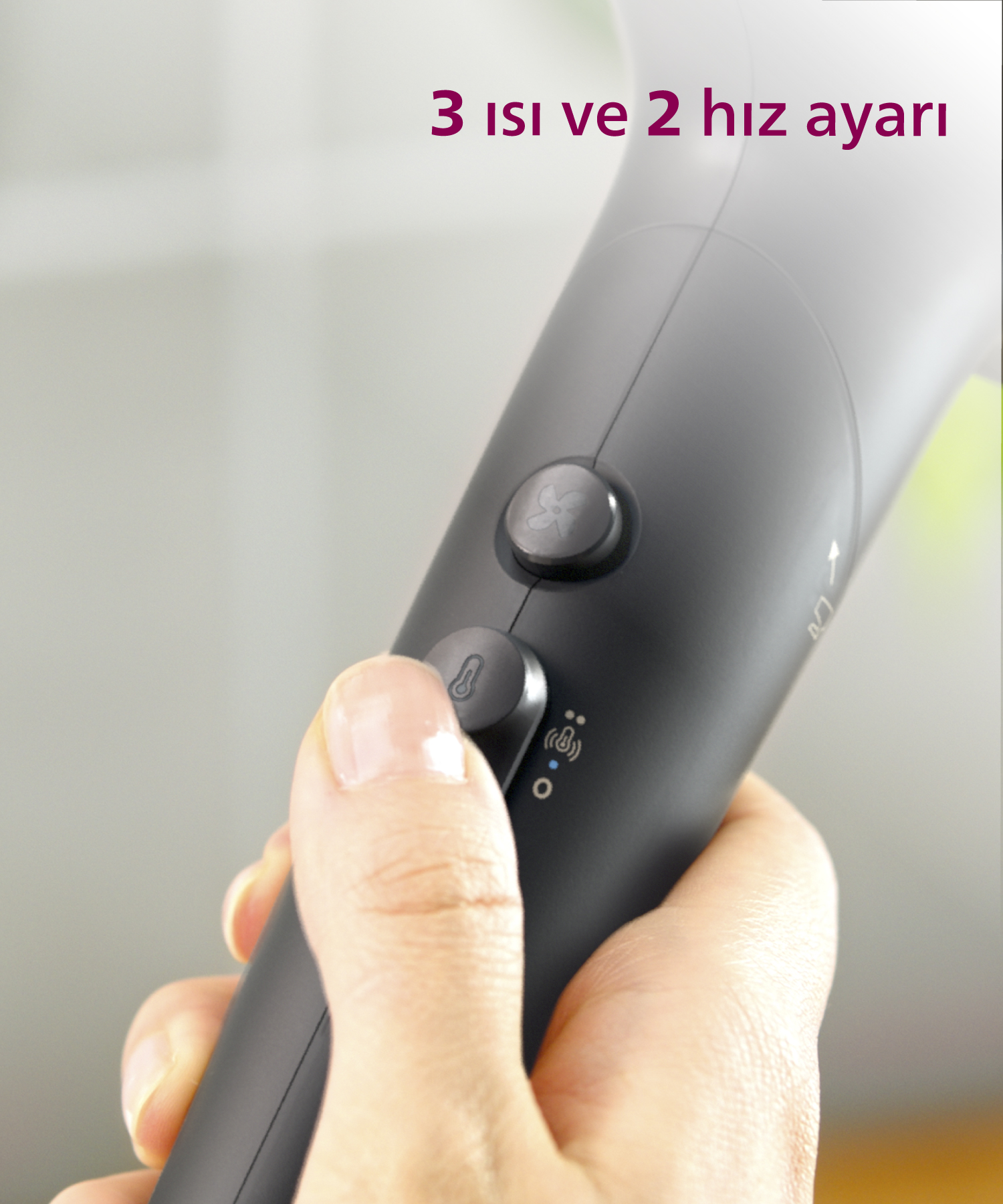 Bir el, düğmeleri olan koyu renkli bir saç kurutma makinesi tutuyor. "3 ısı ve 2 hız ayarı".
