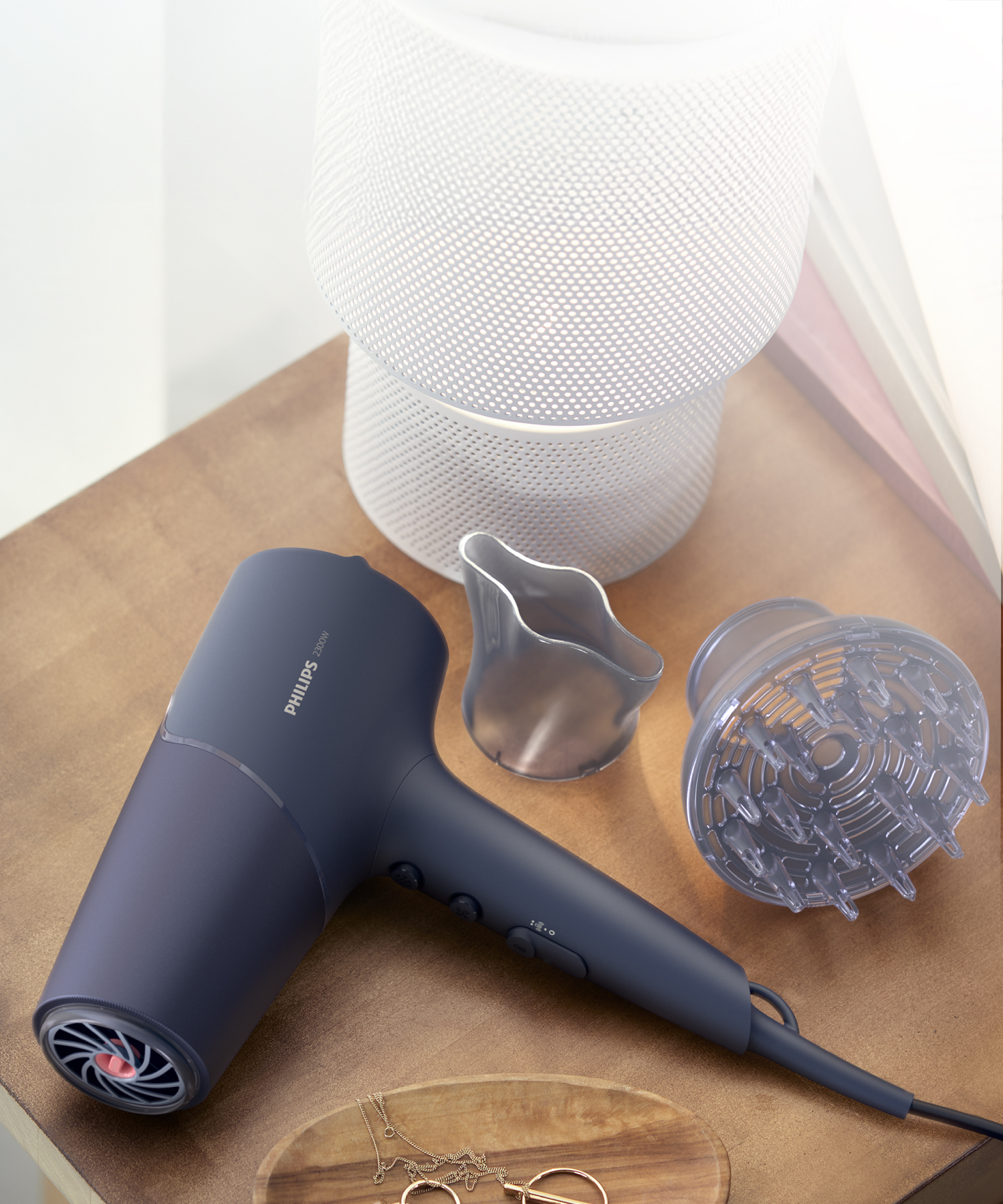 Ataşmanlı koyu renkli Philips saç kurutma makinesi ahşap bir masada duruyor.
