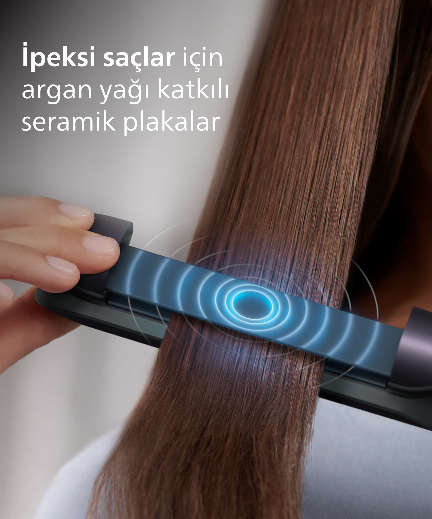El, mavi dalgalar gösteren düzleştiriciyle kahverengi saçı düzleştiriyor.