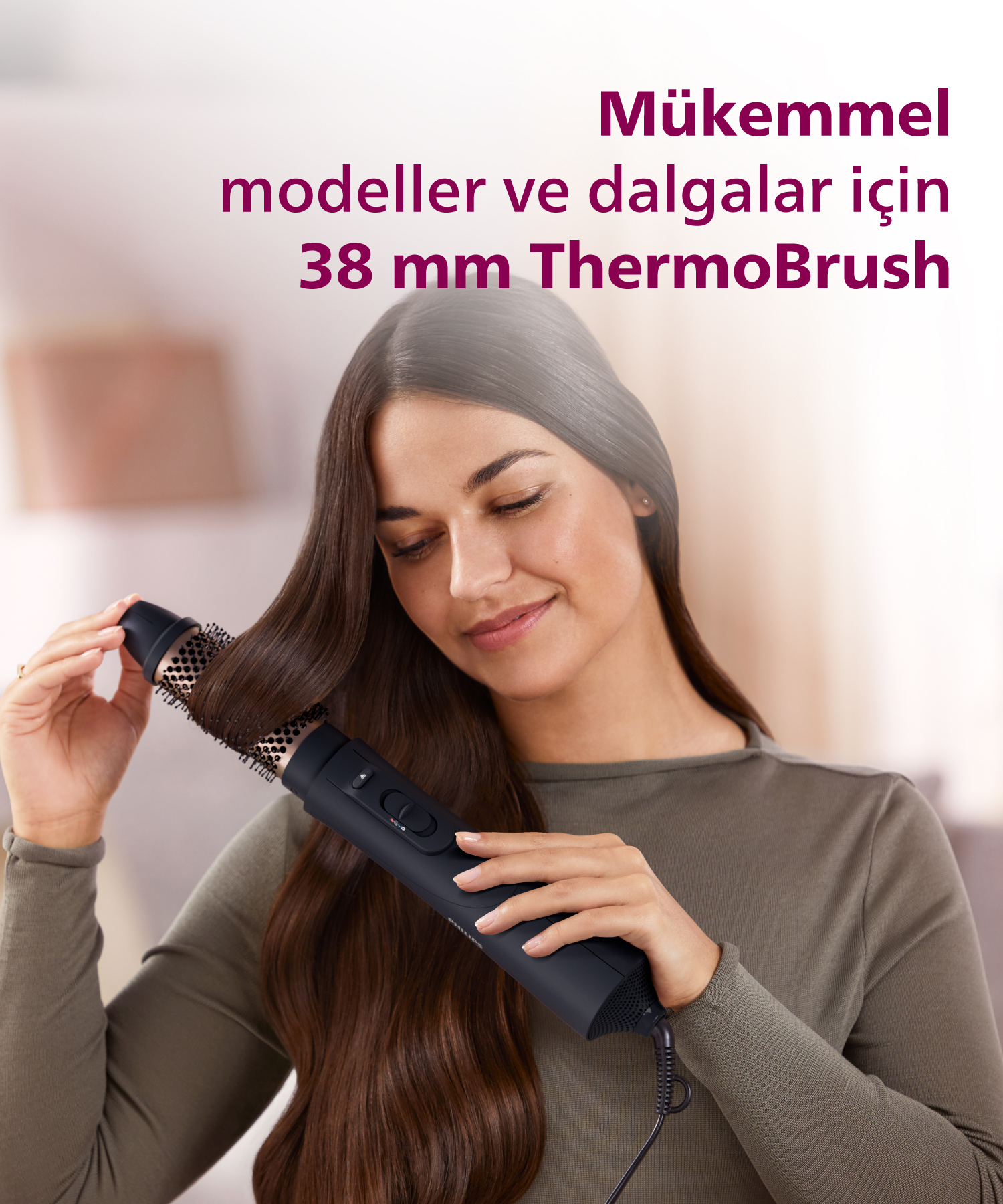 Kadın uzun kahverengi saçını siyah ThermoBrush saç şekillendiriciyle yapıyor.