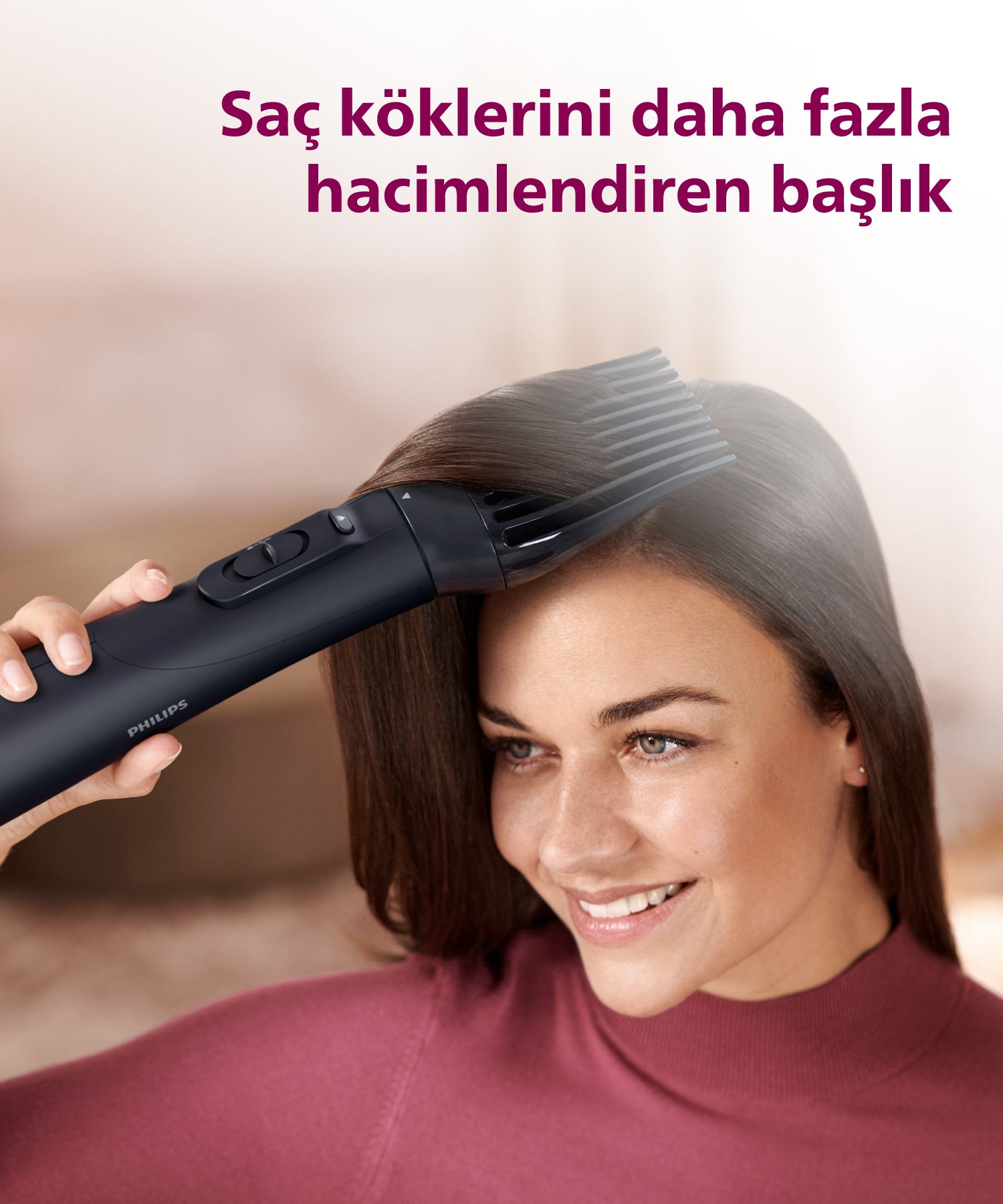 Bir kadın saçını Philips marka siyah saç kurutma makinesiyle şekillendiriyor.