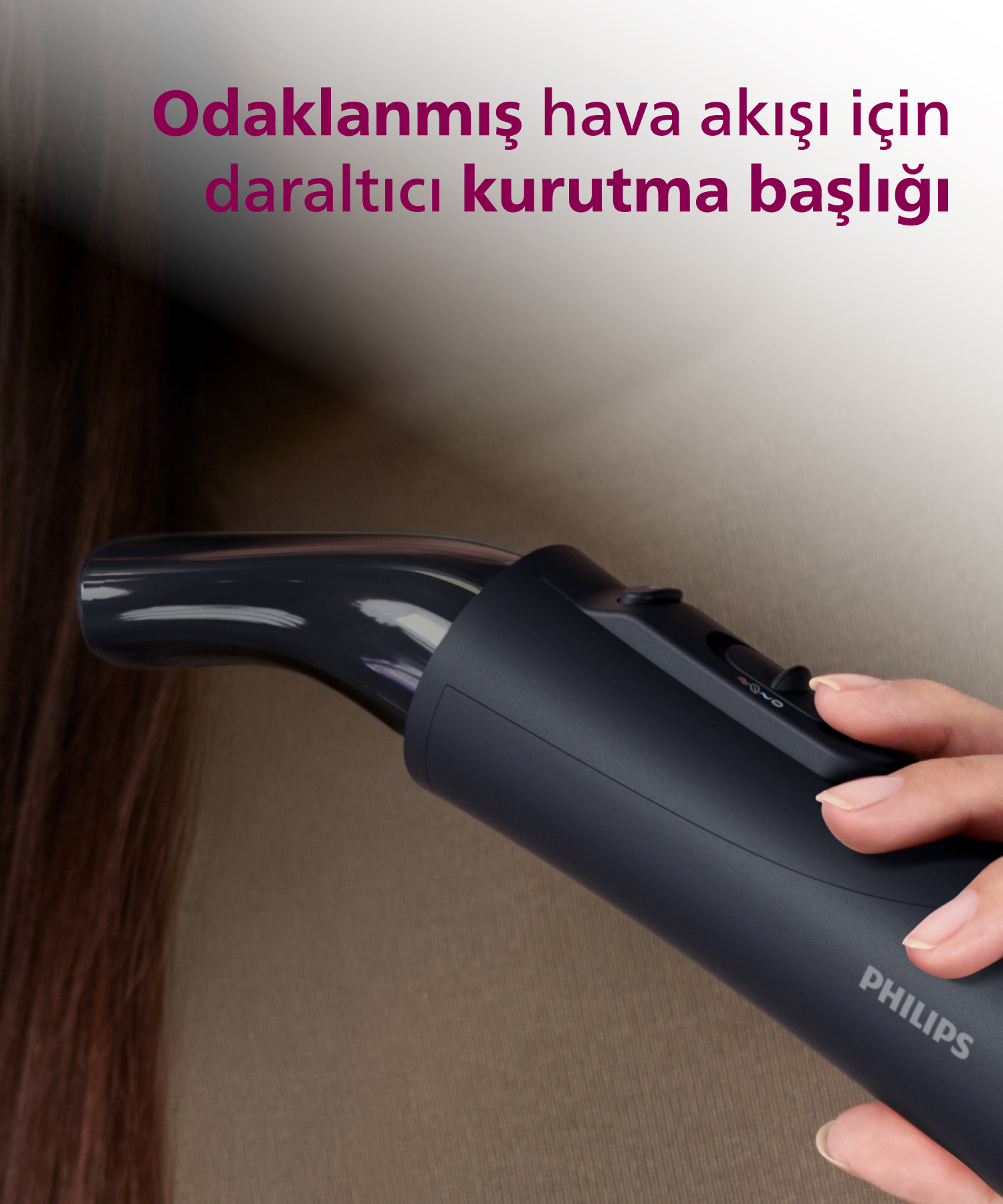 Bir el, koyu renk saç üzerinde dar başlığa sahip siyah Philips saç kurutma makinesi tutuyor.