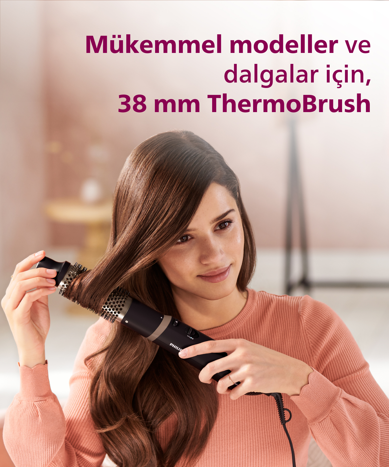 Uzun kahverengi saçlı kadın, siyah ThermoBrush ile saçını şekillendiriyor.
