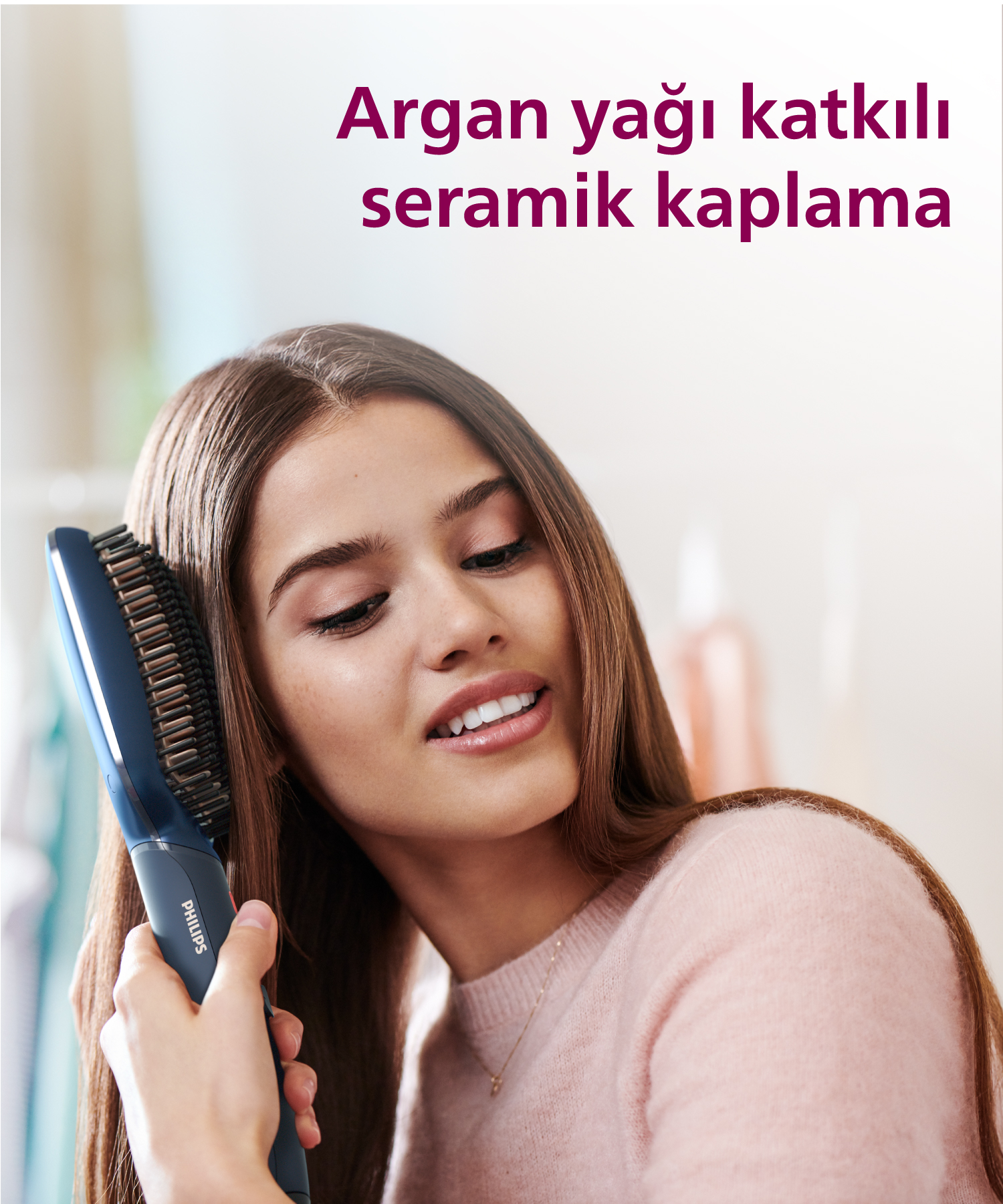 Genç bir kadın mavi Philips saç fırçasıyla kahverengi saçlarını tarıyor.