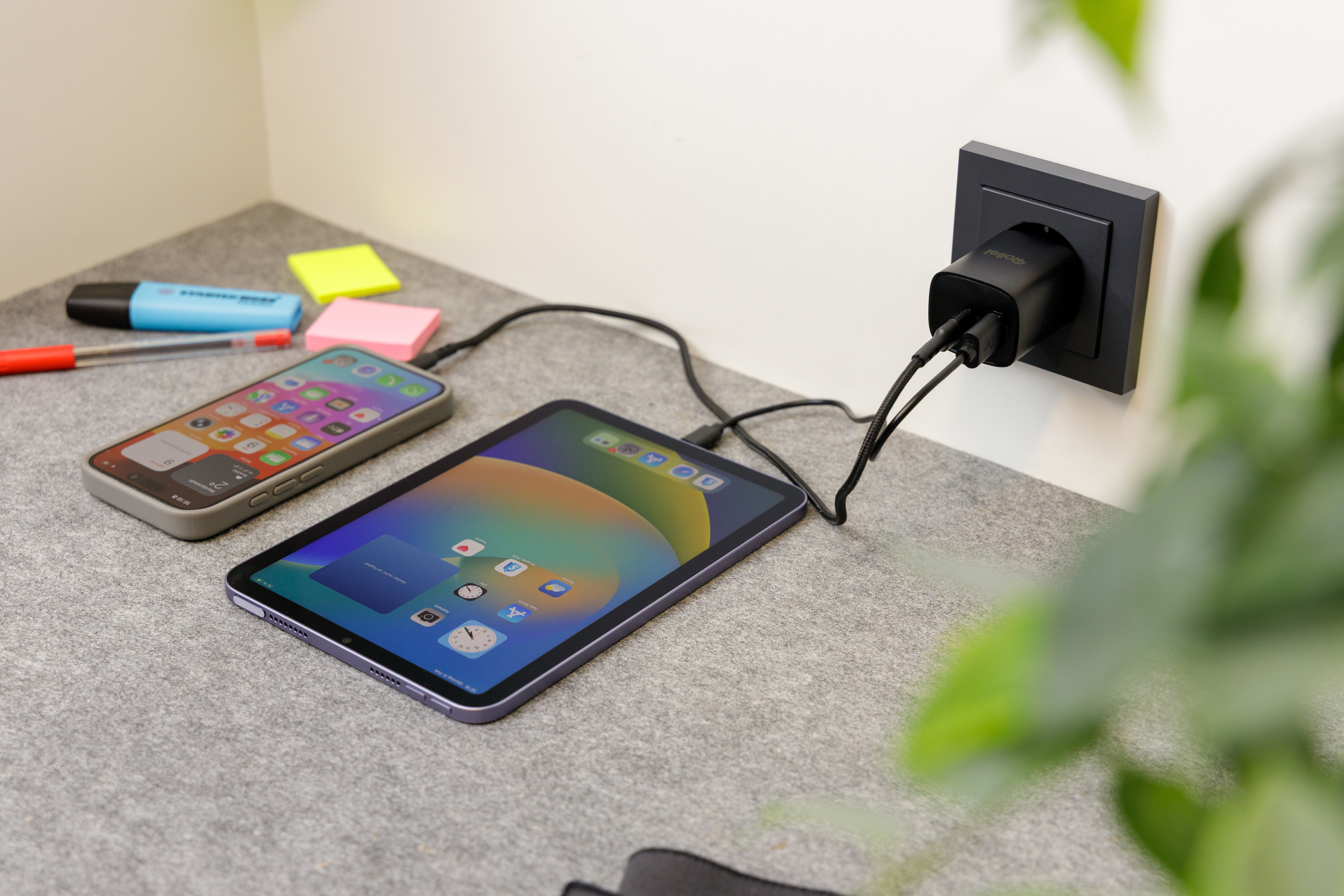 Ein Smartphone und ein Tablet werden an eine Steckdose geladen.