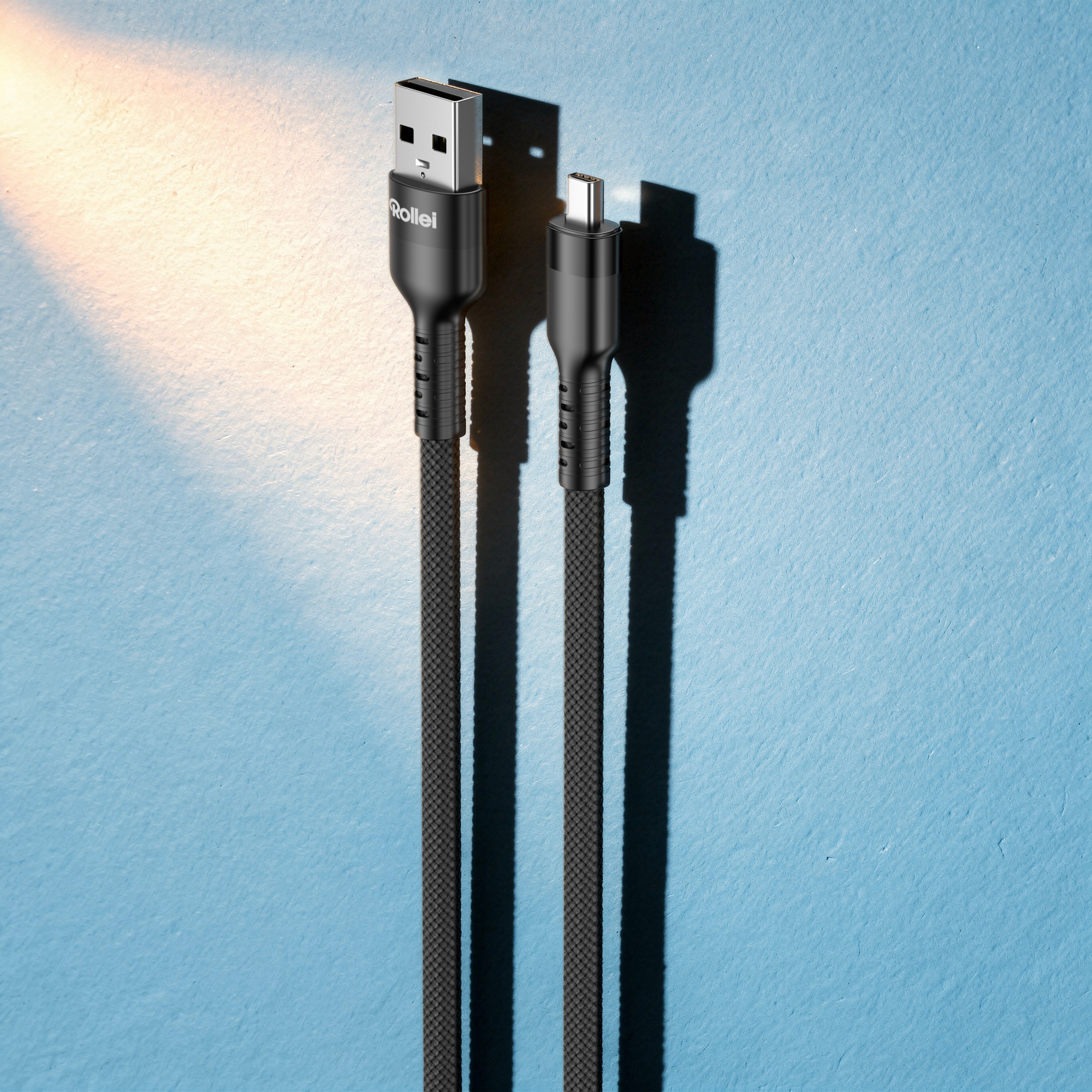 Zwei schwarze USB-Kabel mit Stoffummantelung liegen auf blauem Hintergrund.