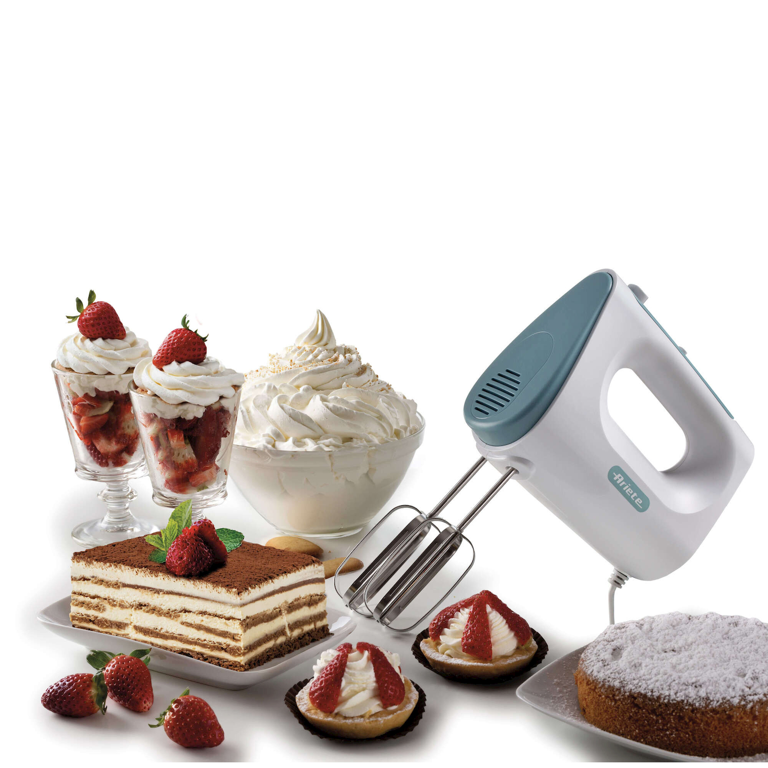 Un frullatore a mano accanto a vari dessert con panna e fragole.