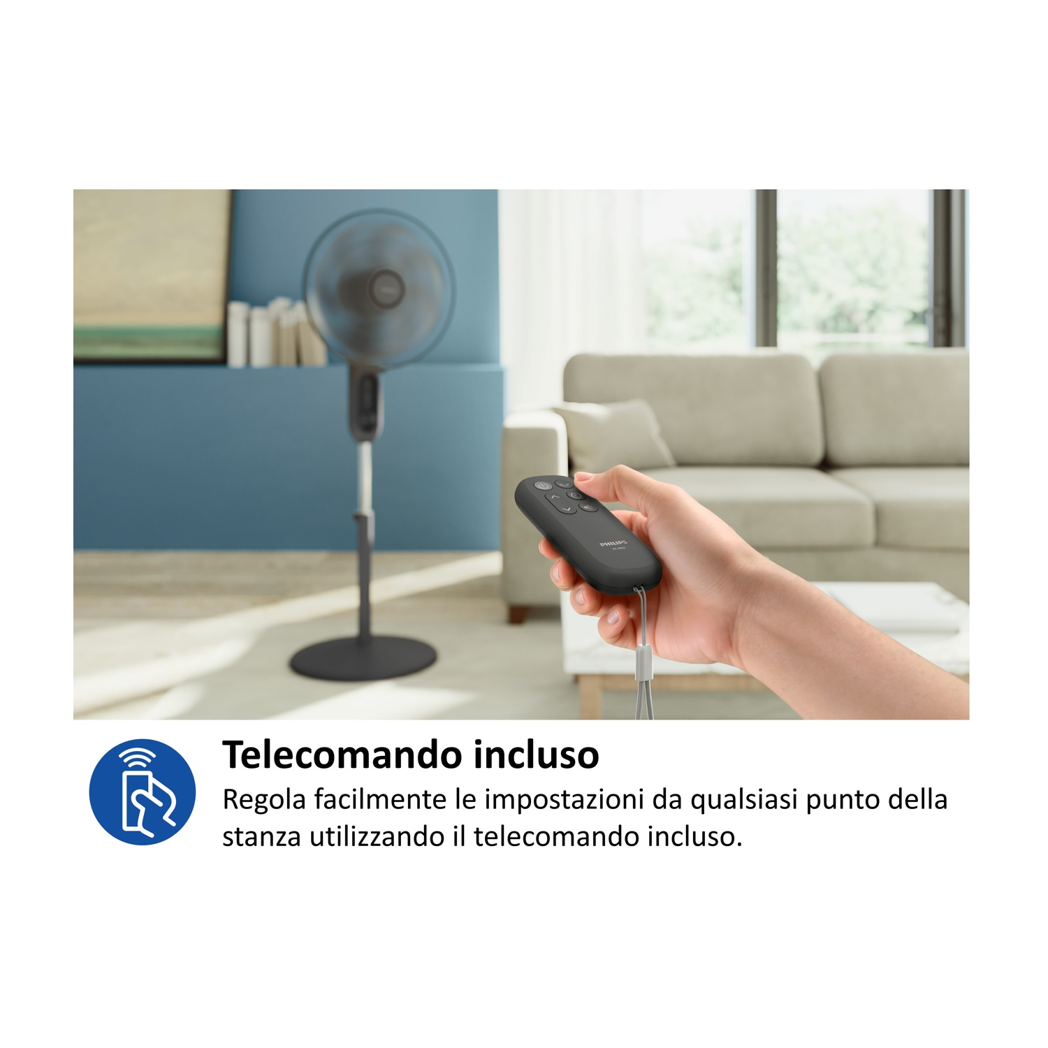 Una mano tiene un telecomando davanti a un ventilatore e un divano.