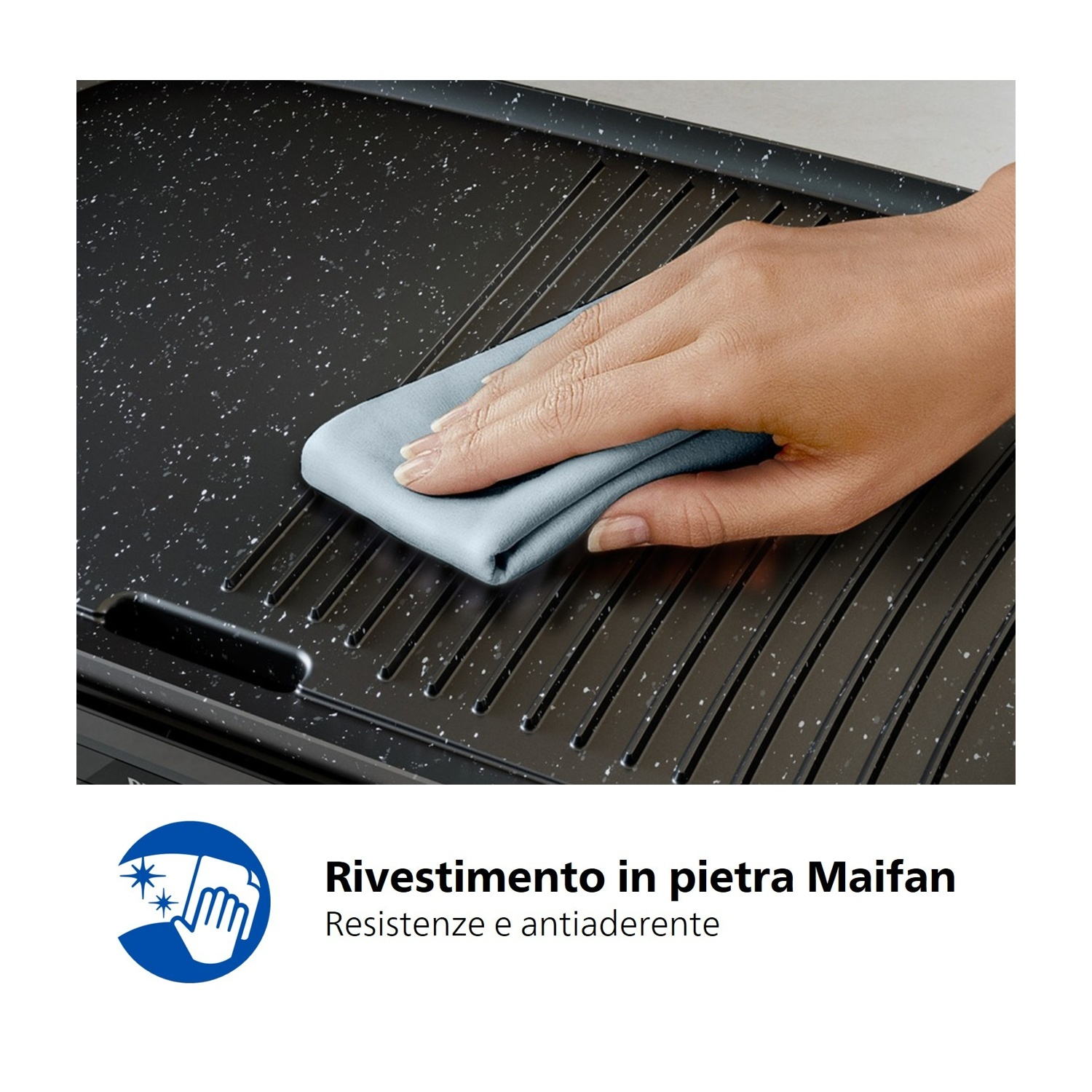 Mano pulisce piastra grill nera con scanalature e macchioline bianche con panno blu.