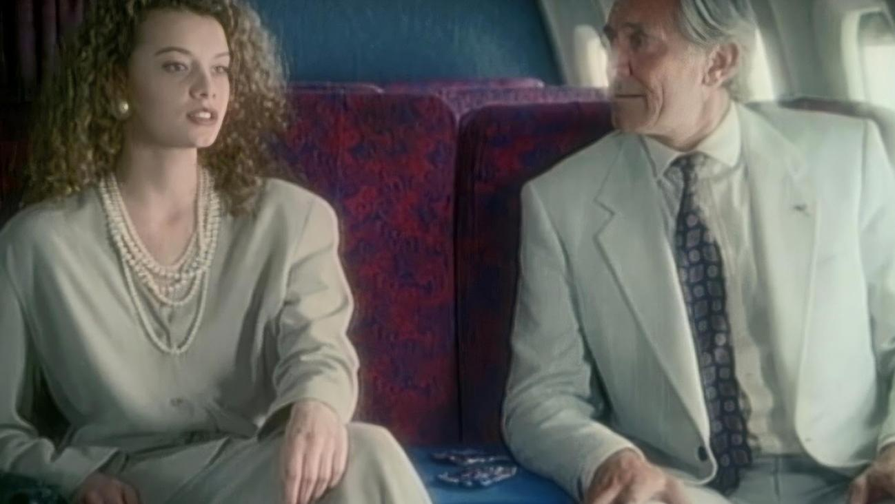 Eine junge Frau und ein älterer Mann sitzen nebeneinander in einem Flugzeug.