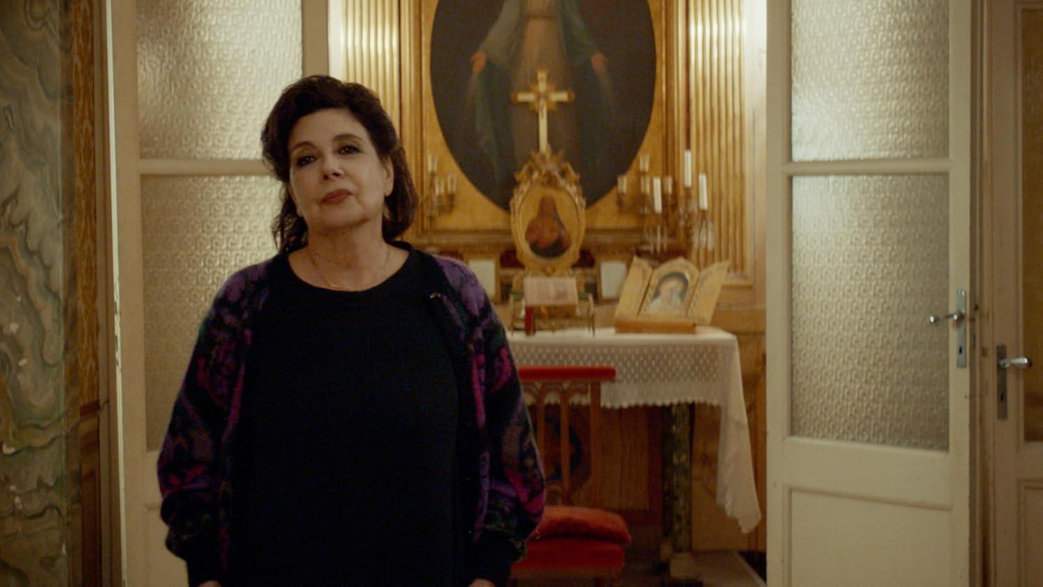 Eine Frau steht vor einem Altar mit religiösen Bildern und Kerzen.