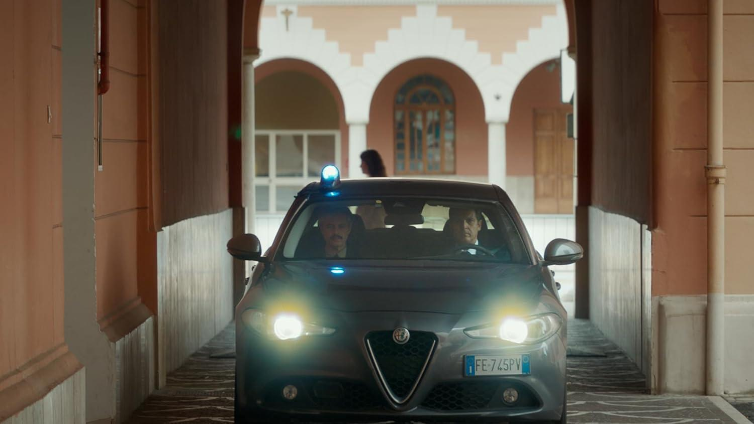 Ein Polizeiauto fährt durch einen Torbogen, die Lichter leuchten.