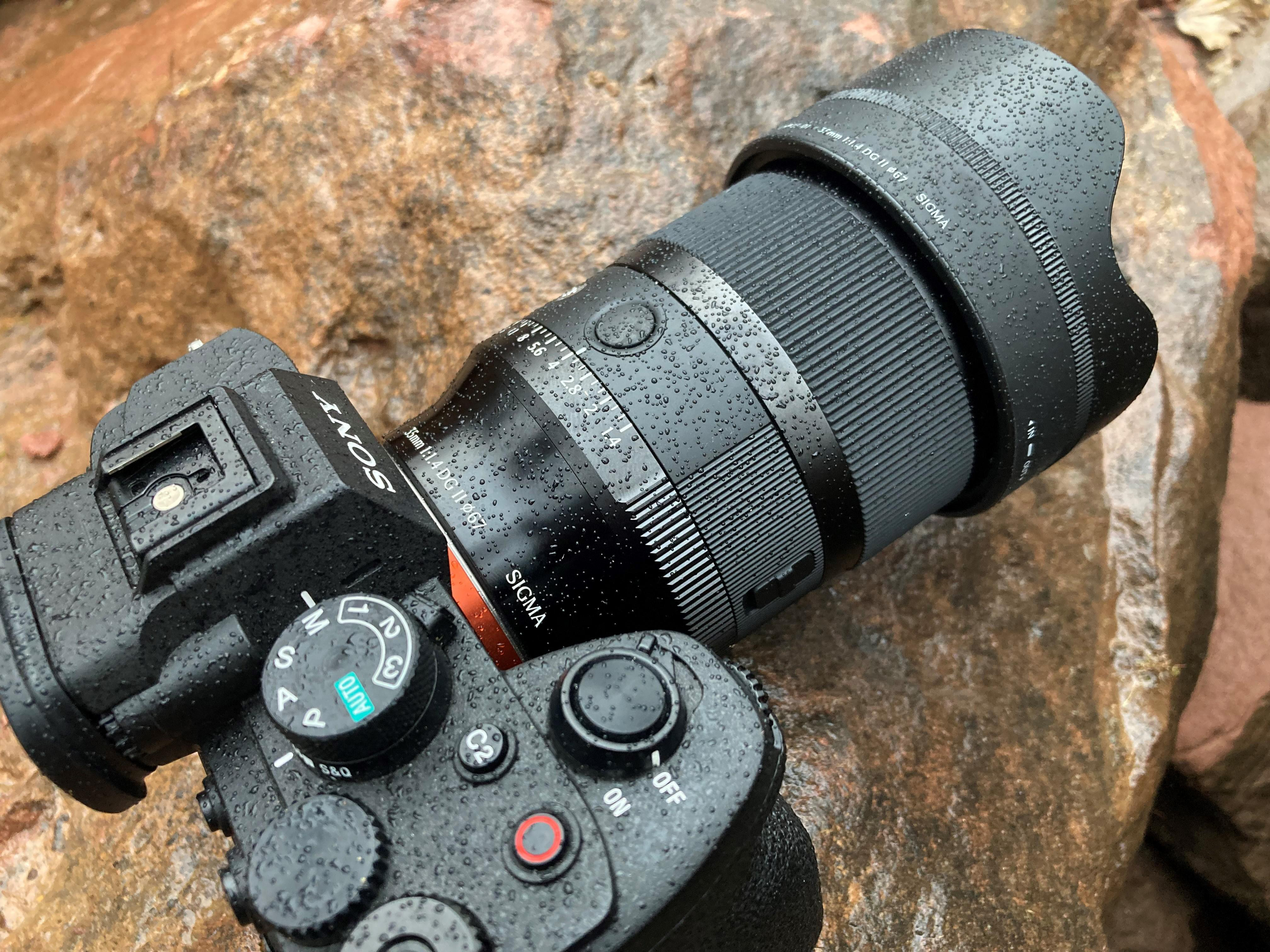 Eine Sony-Kamera mit Sigma-Objektiv liegt auf nassen Felsen.