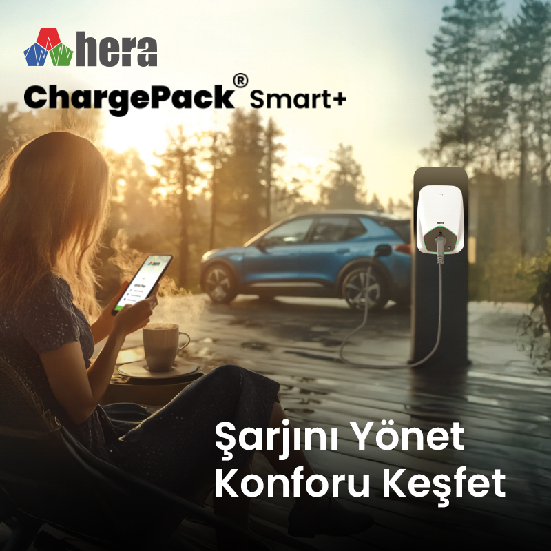 Telefonlu kadın, şarj olan bir elektrikli arabanın yanında oturuyor.