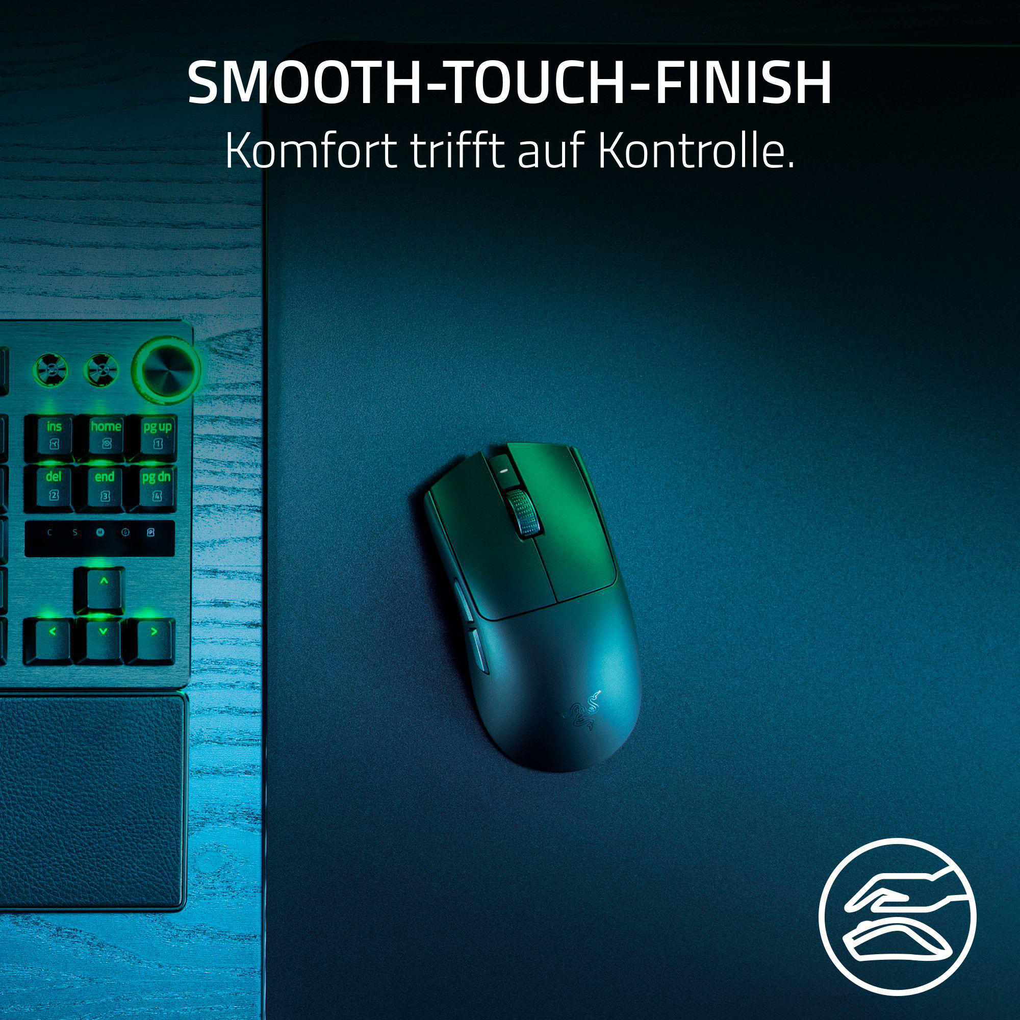 Eine schwarze Maus auf einer dunklen Matte, mit Tastatur im Hintergrund.