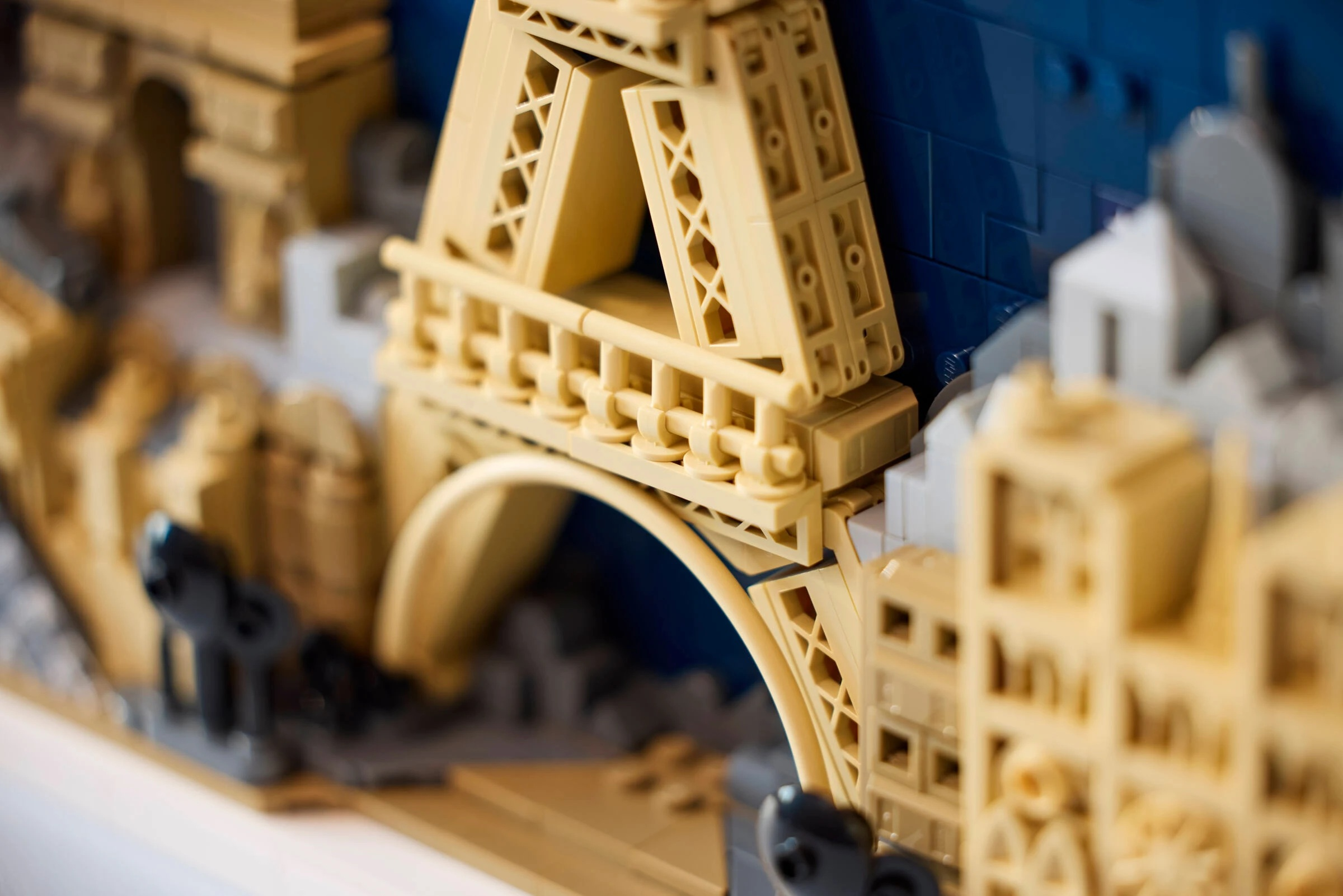 Model Lego mostu z łukami i budynkami na tle niebieskiej wody.